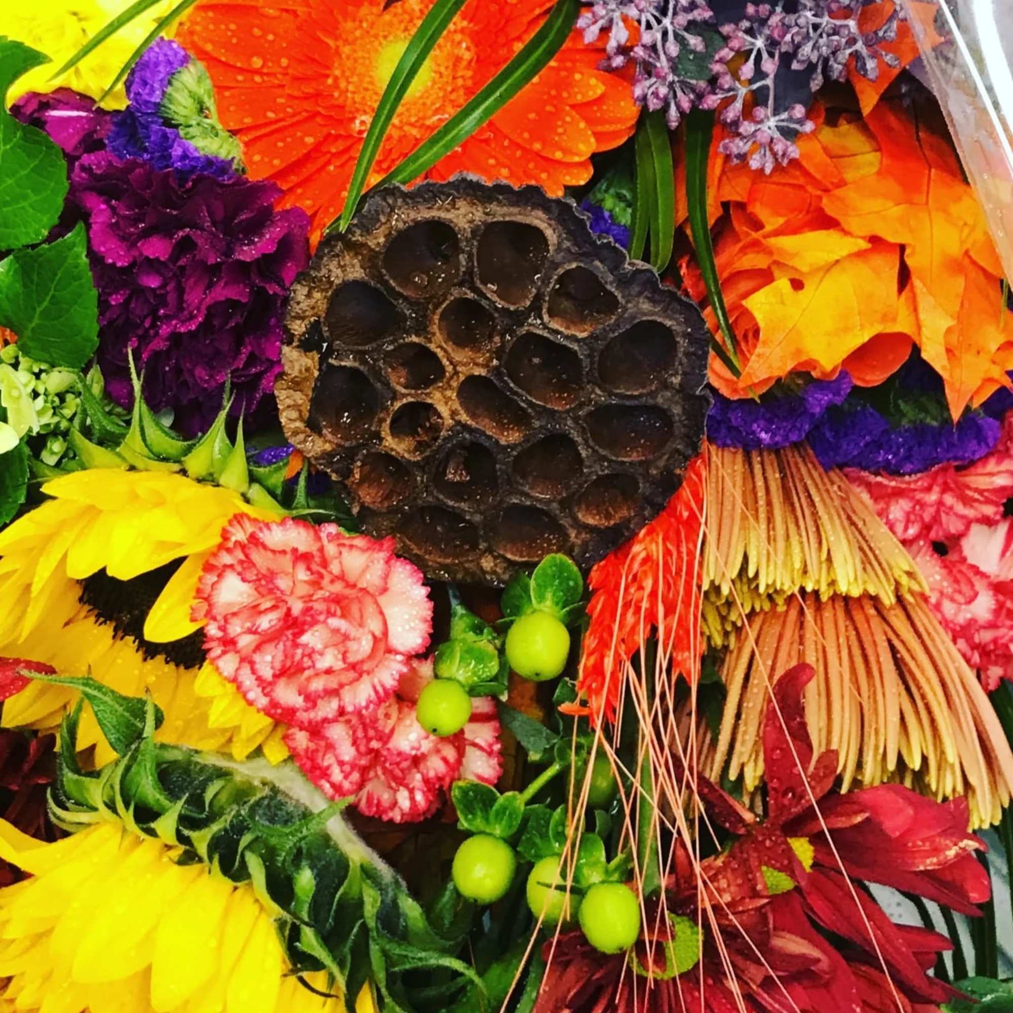 Bright mixed bouquet with sunflowers, gerberas, carnations, and purple filler flowers