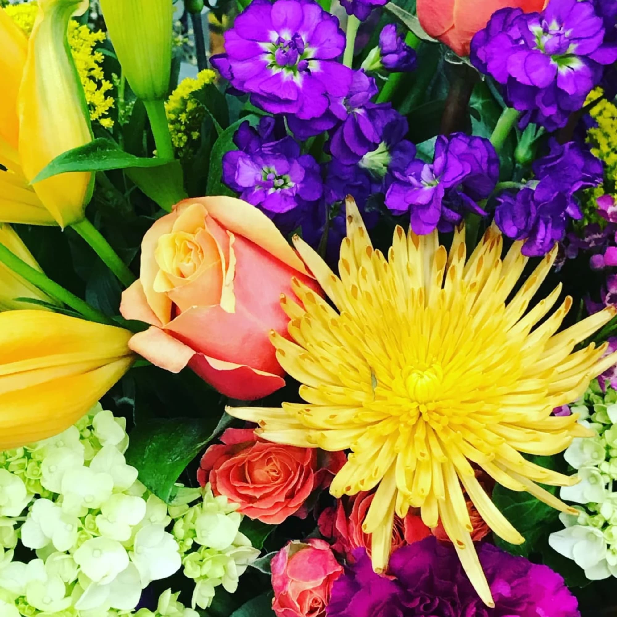 Colorful bouquet with yellow lilies, roses, and purple blooms
