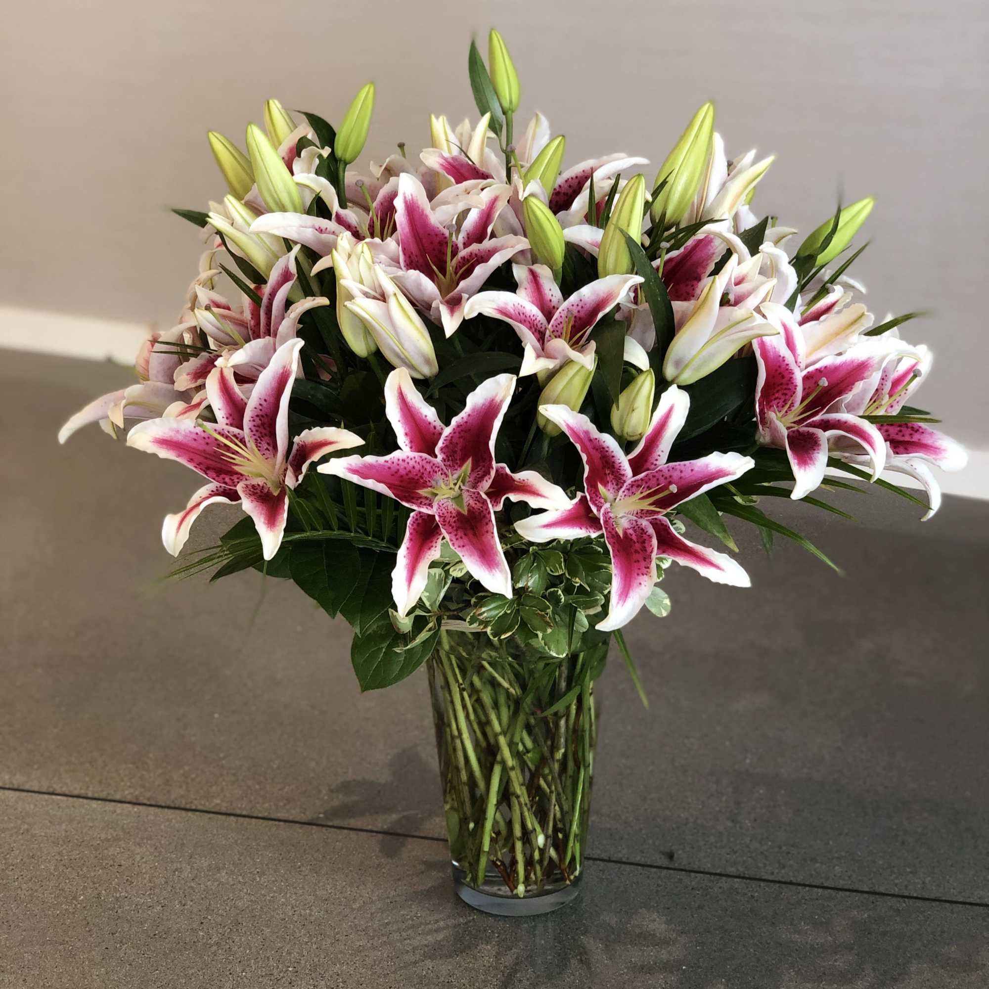 Pink and white lilies arranged in a clear glass vase
