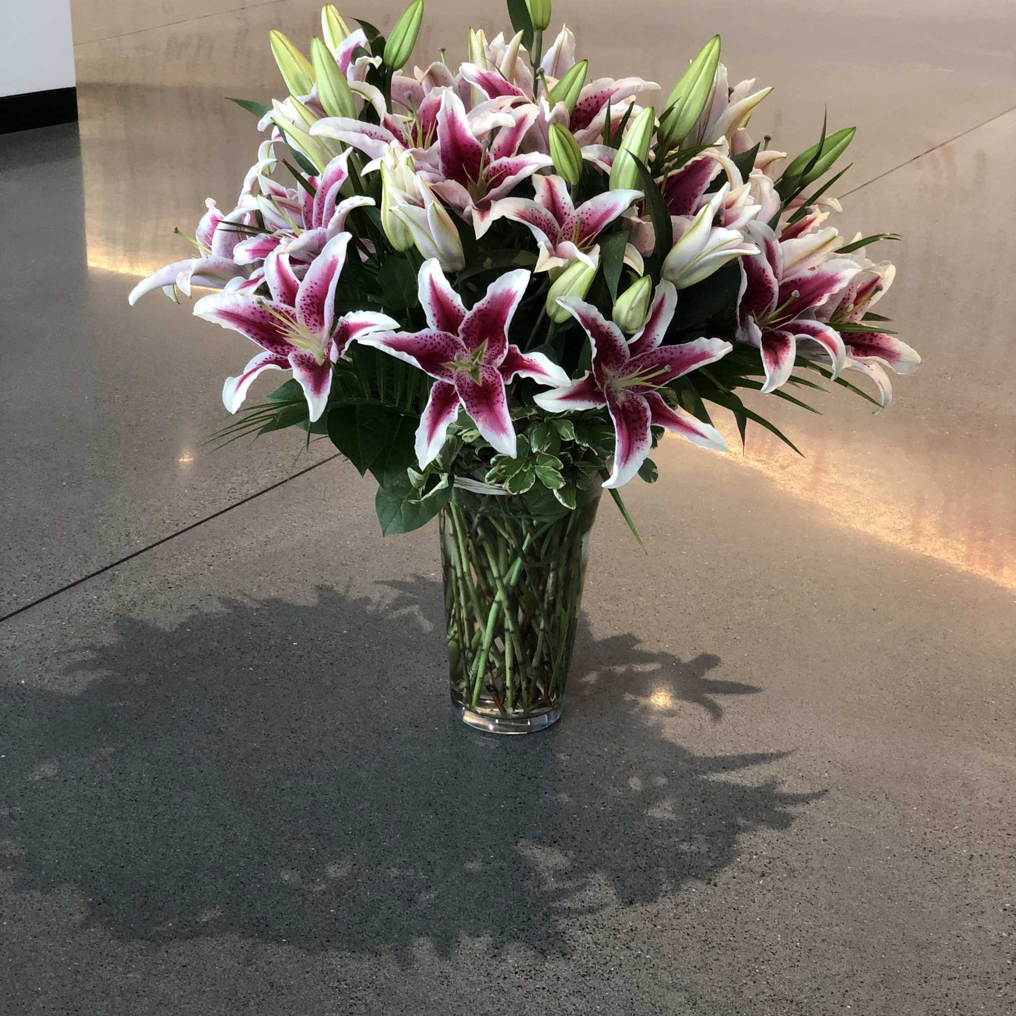 Large bouquet of pink and white lilies in a clear glass vase