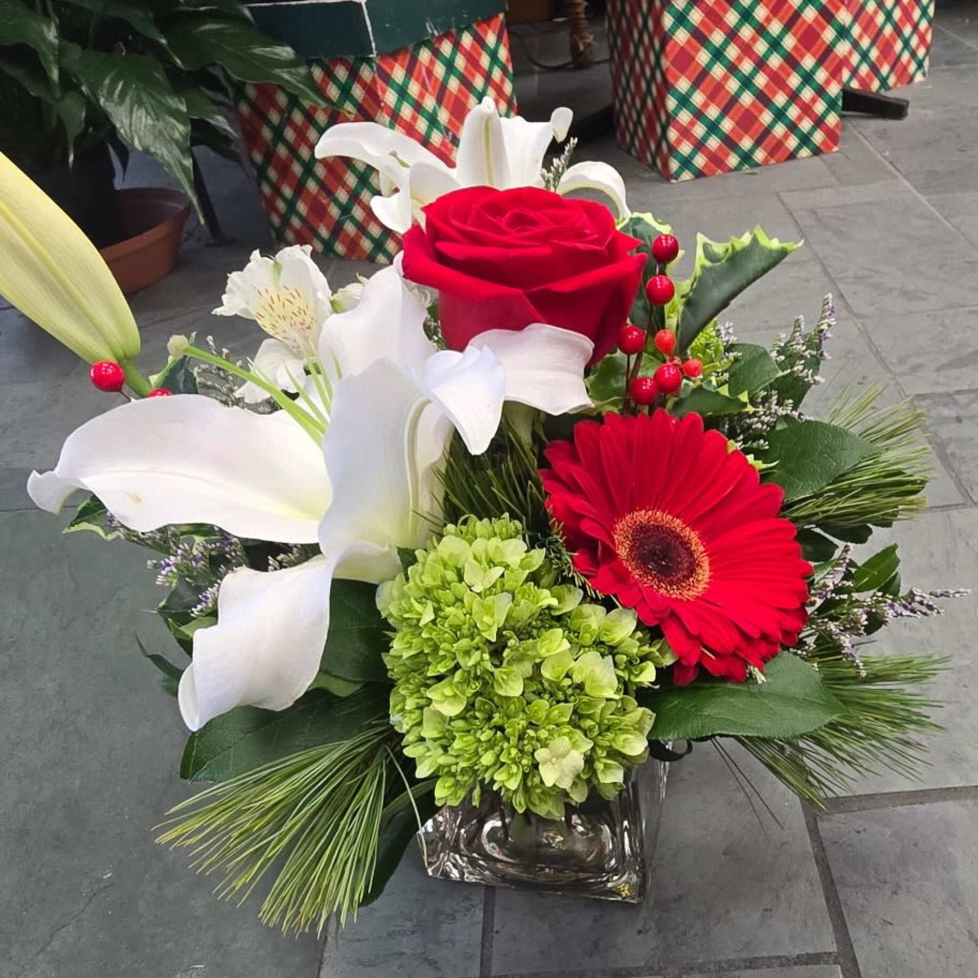 Red rose and white lily arrangement in a glass vase with a red gerbera daisy