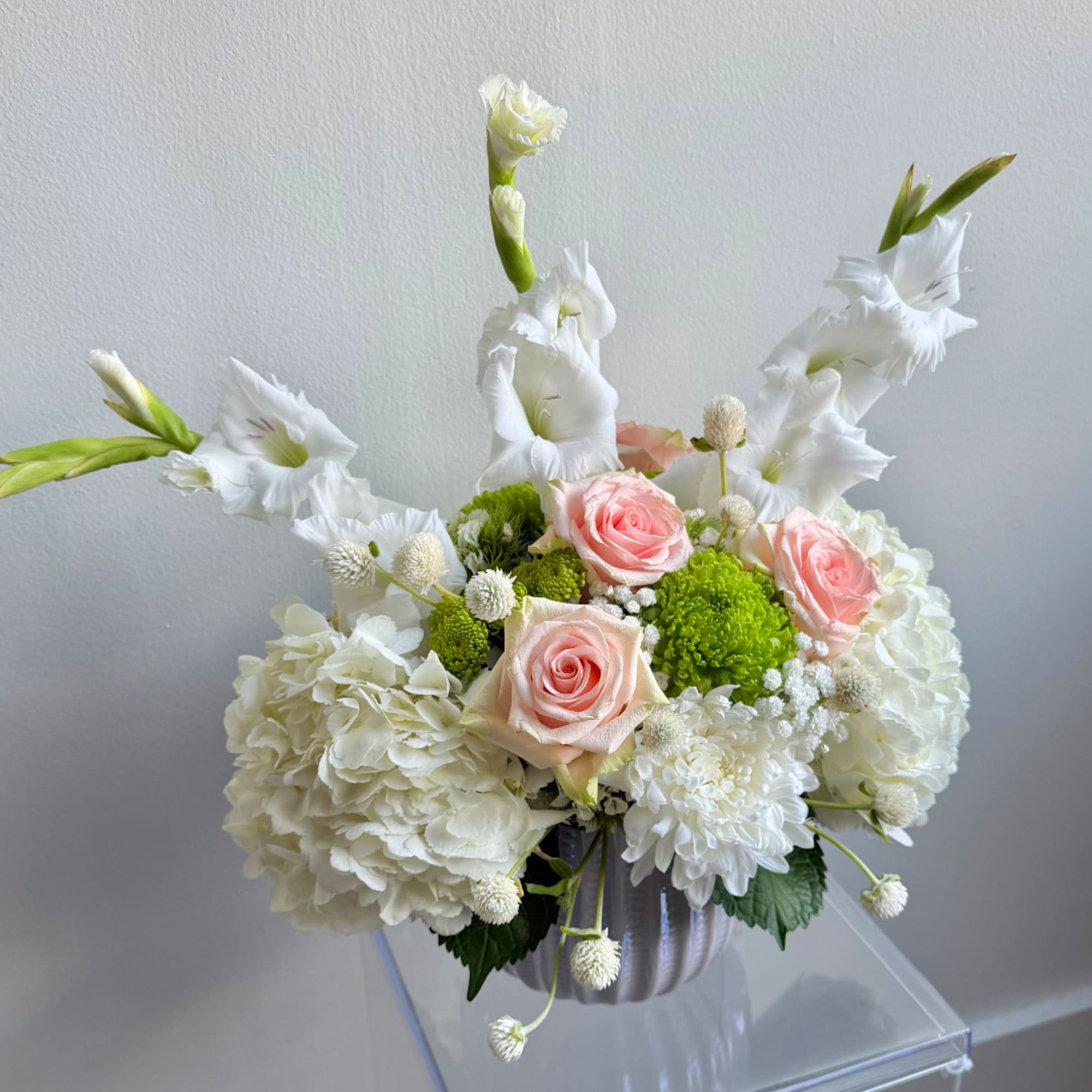 White and pink floral arrangement in a ribbed vase with tall white blooms