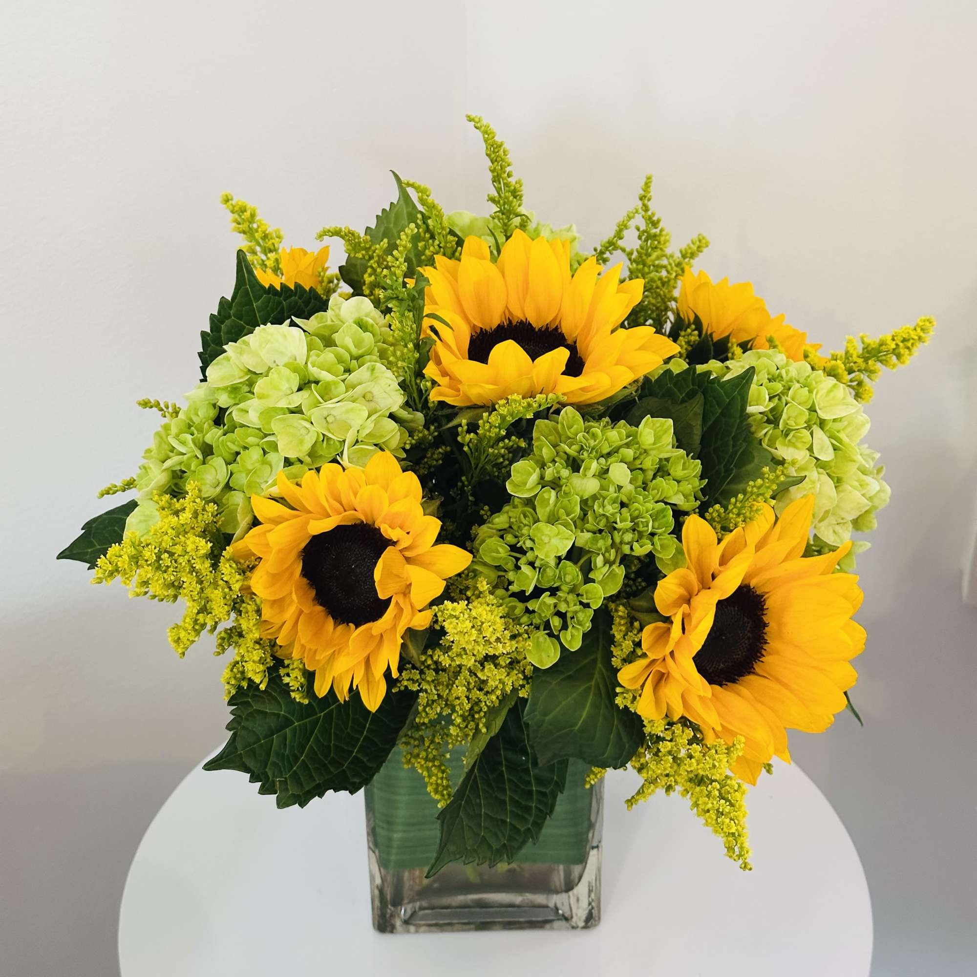 Sunflowers and green hydrangeas in a clear glass vase