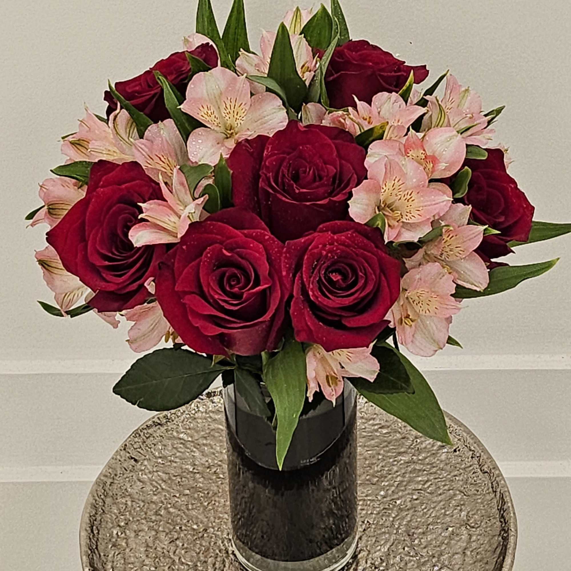 Bouquet of red roses and pale pink alstroemeria in a black vase