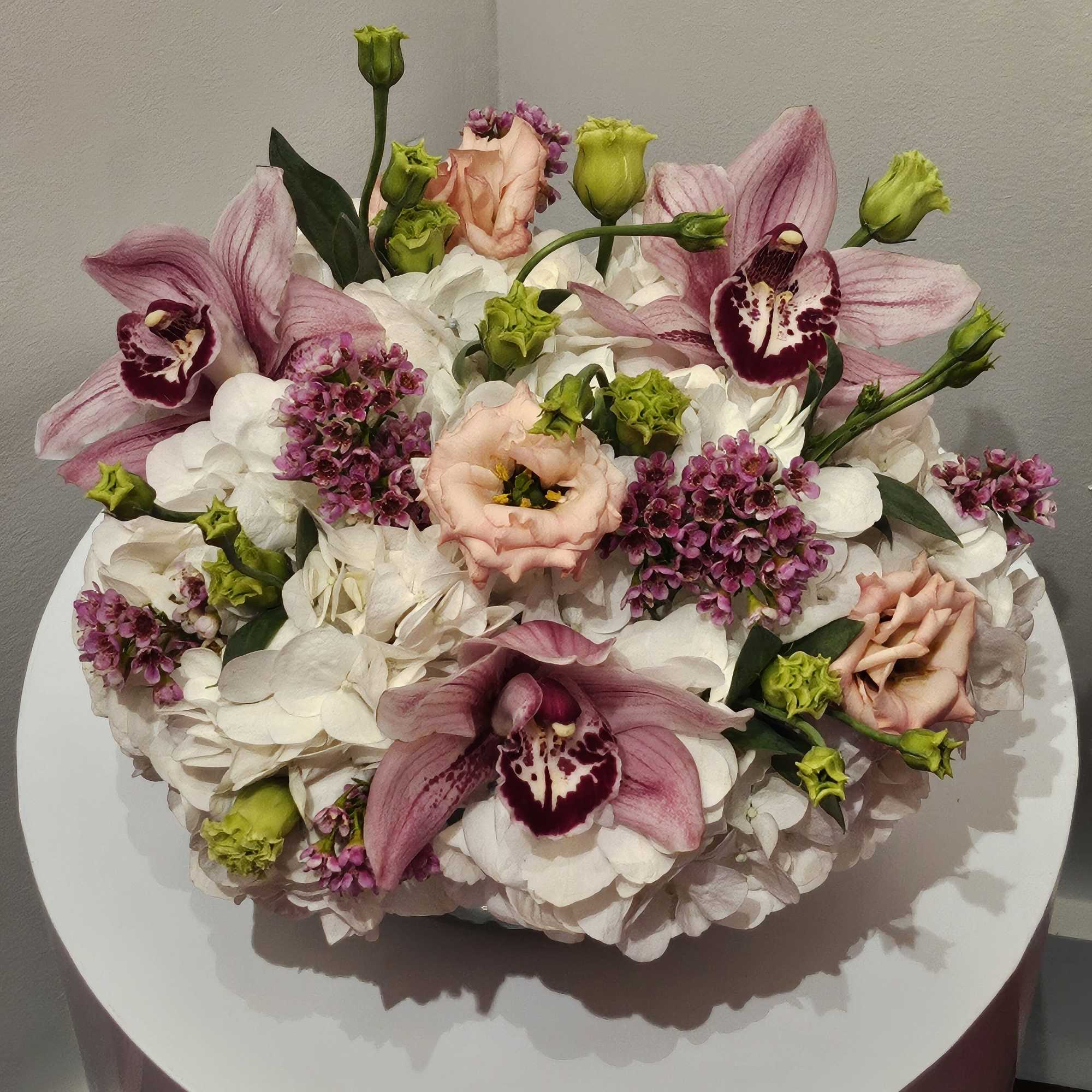 Pink orchids and white hydrangeas arranged in a low round centerpiece
