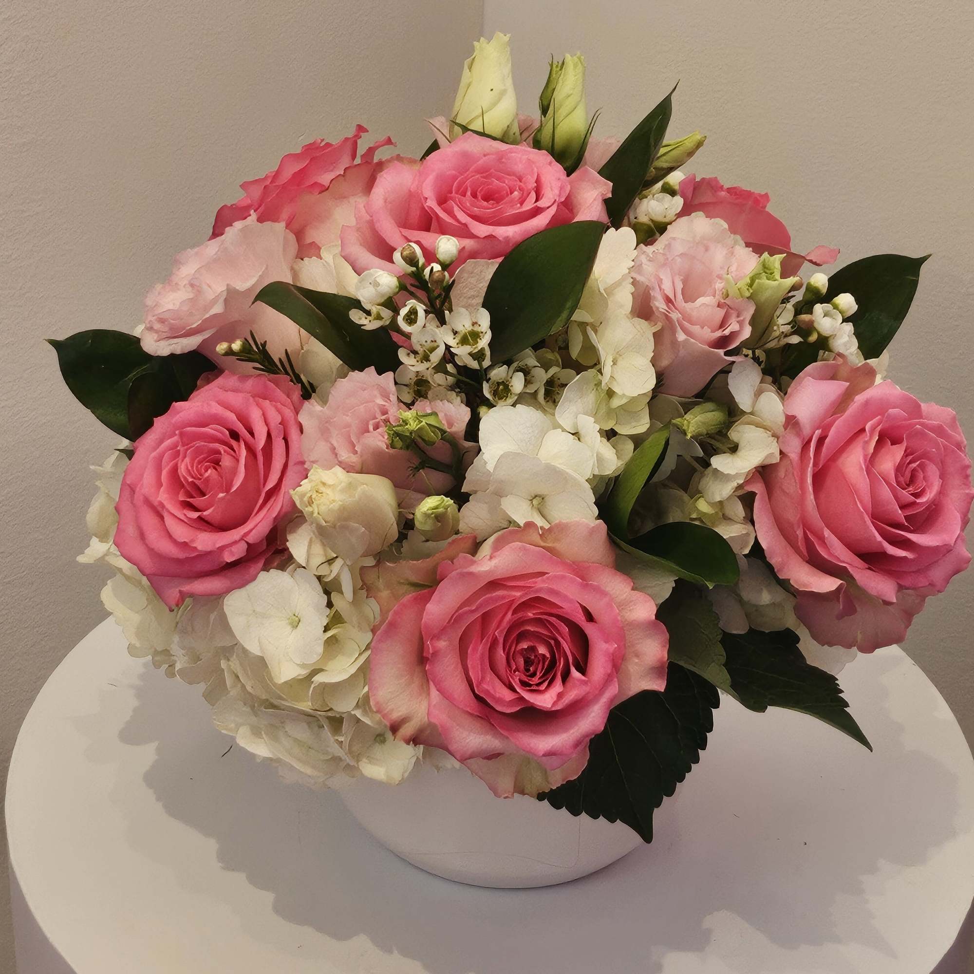 Pink roses and white hydrangeas arranged in a white bowl vase