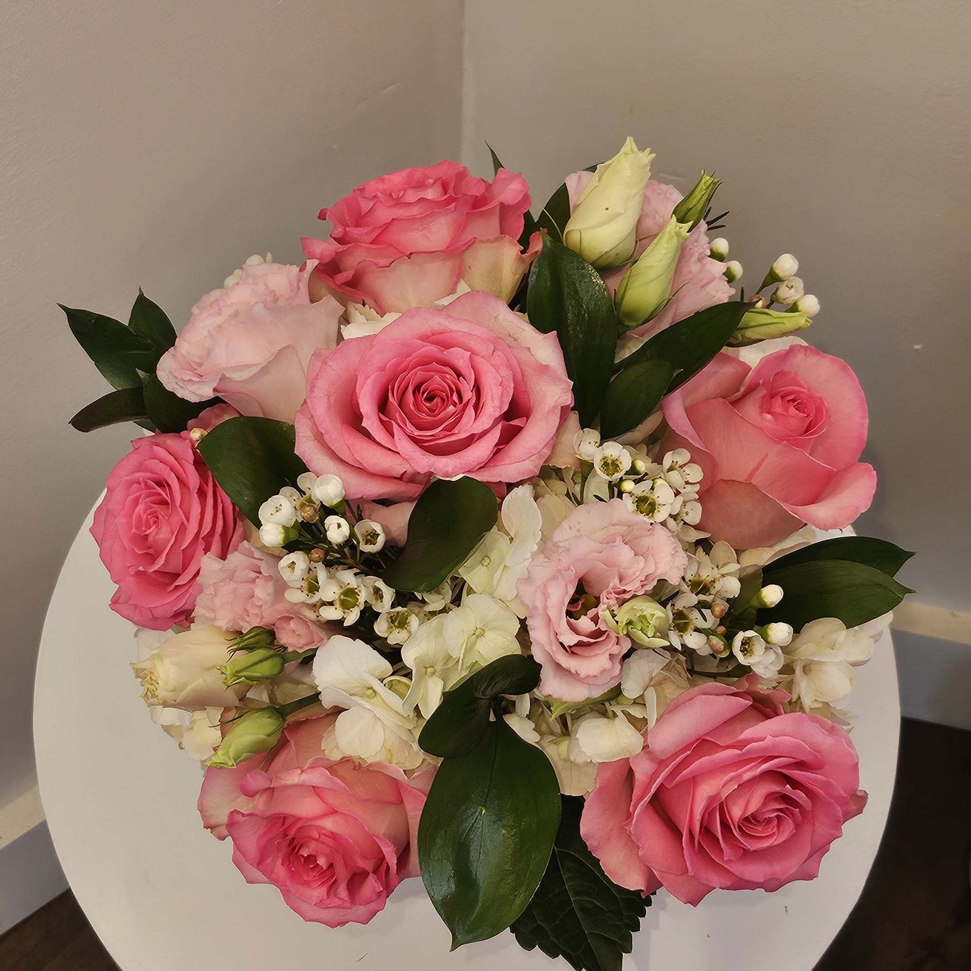 Pink roses and white blooms arranged in a round bouquet