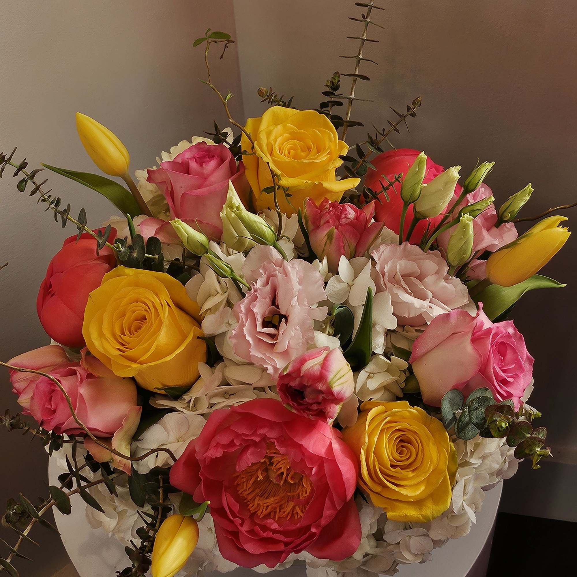 Mixed bouquet of pink and yellow roses with tulips in a white box