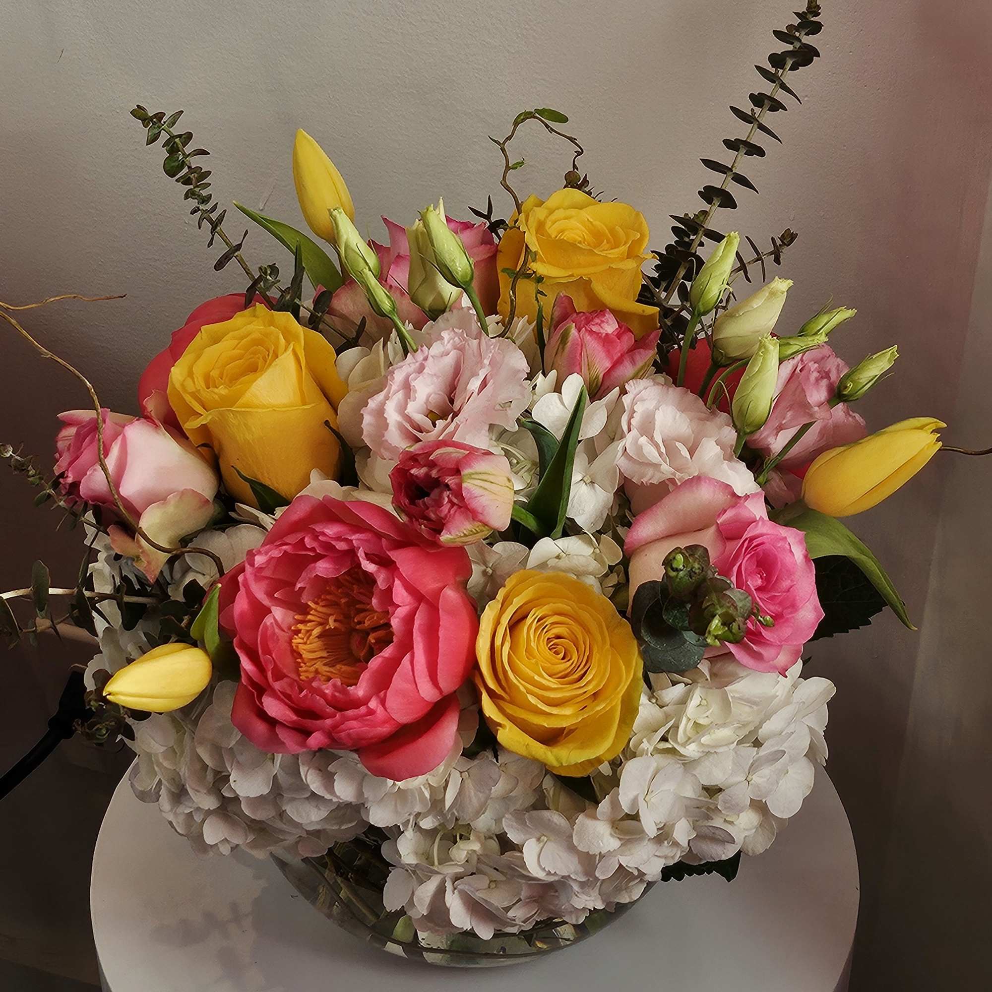 Bouquet of pink and yellow roses with white hydrangeas in a glass vase