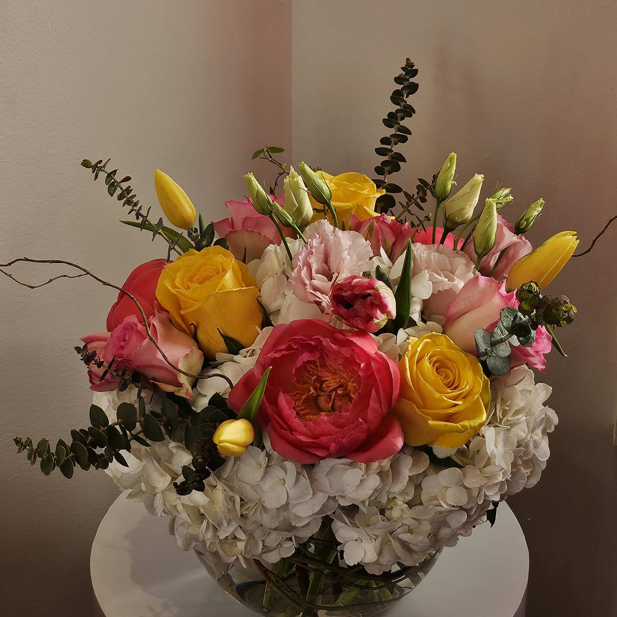 Colorful bouquet of roses, tulips, and hydrangeas in a glass vase
