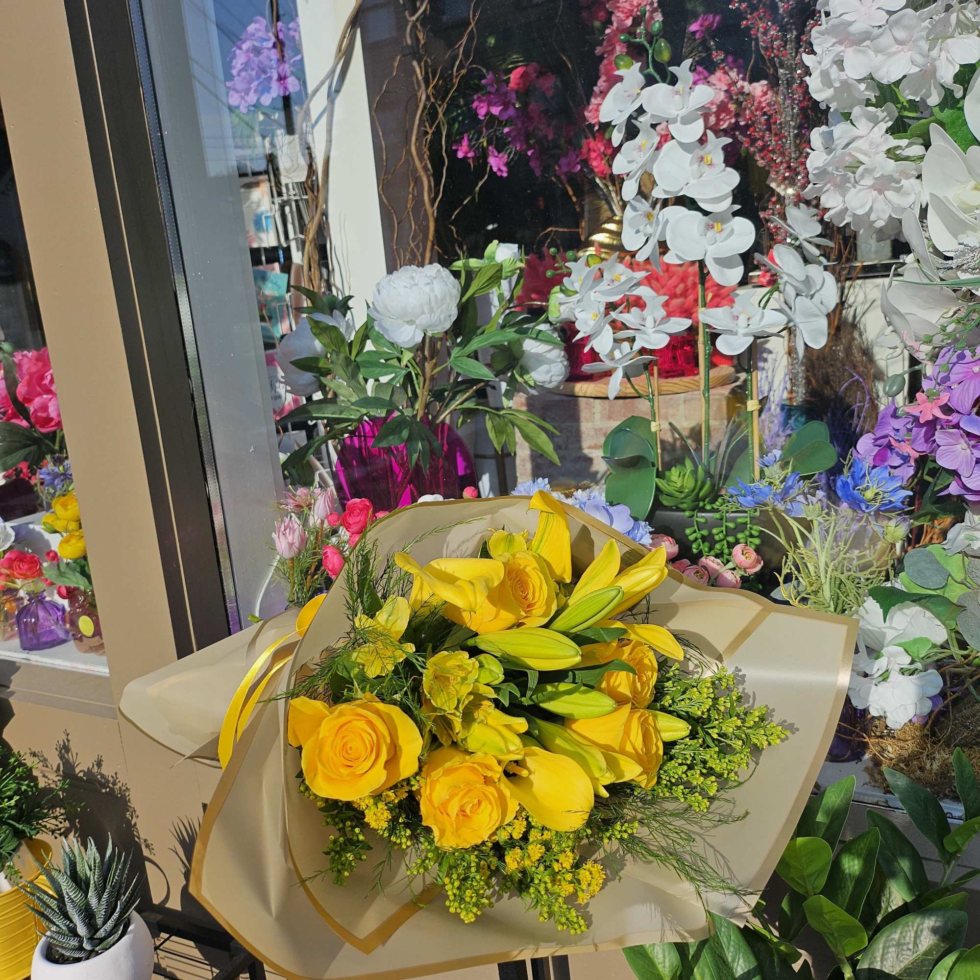 Yellow bouquet of roses and lilies wrapped in beige paper