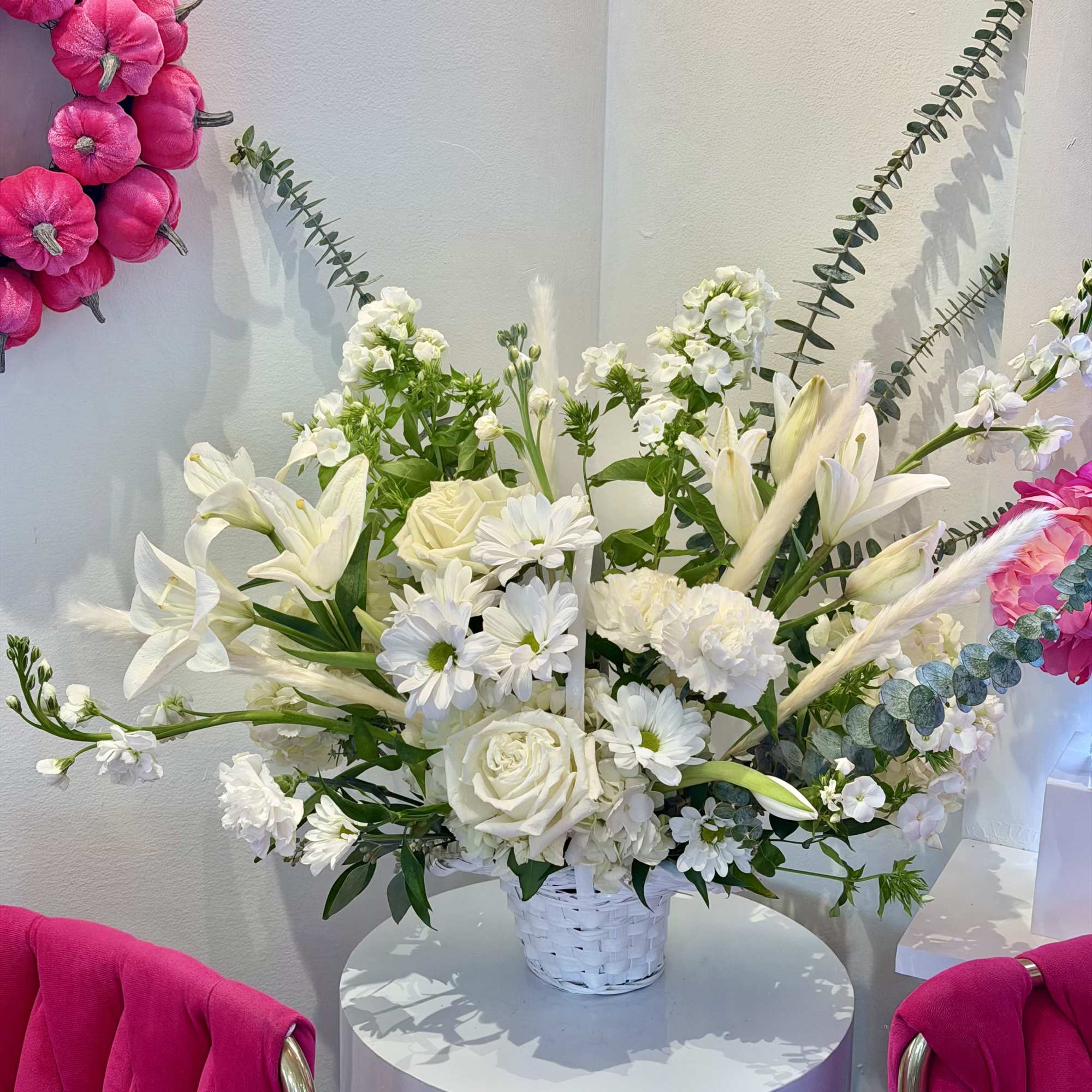 White floral arrangement in a white basket with pink wall accents