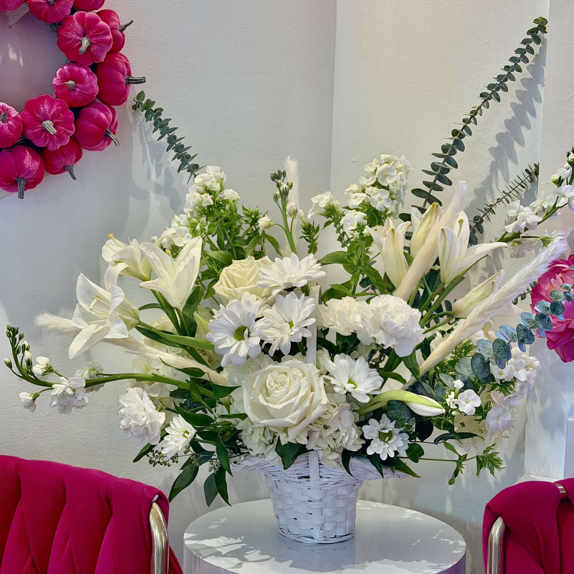 White floral arrangement in a white basket on a round pedestal
