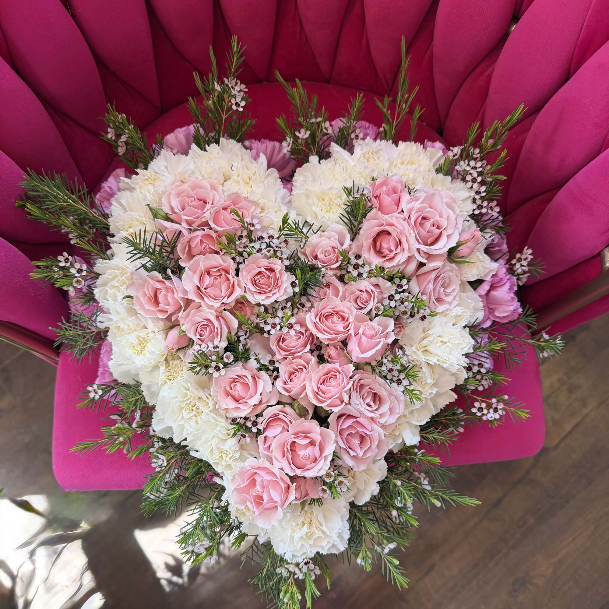 A heart-shaped floral arrangement of blush pink roses layered over creamy white