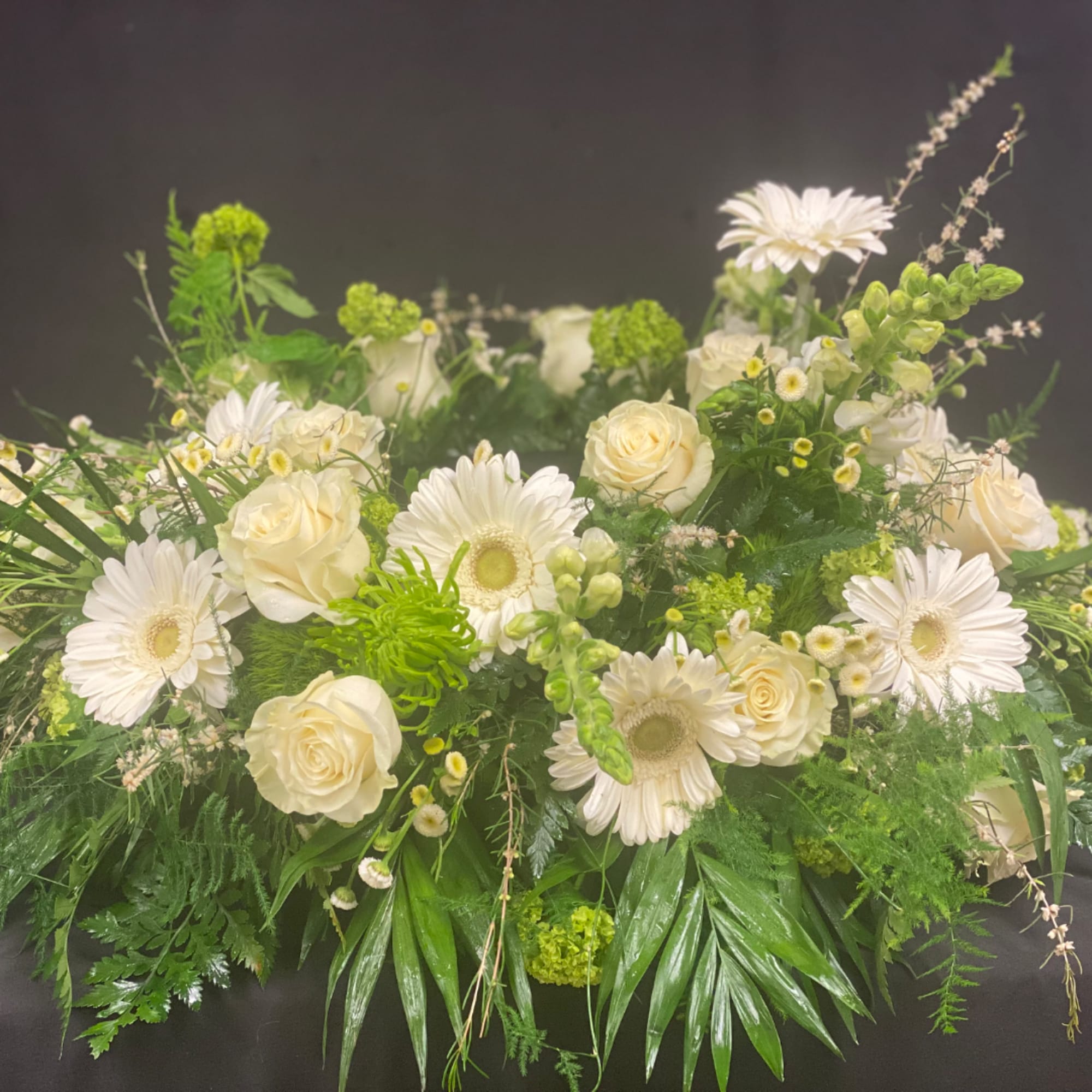 White roses and gerbera daisies arranged with green accents