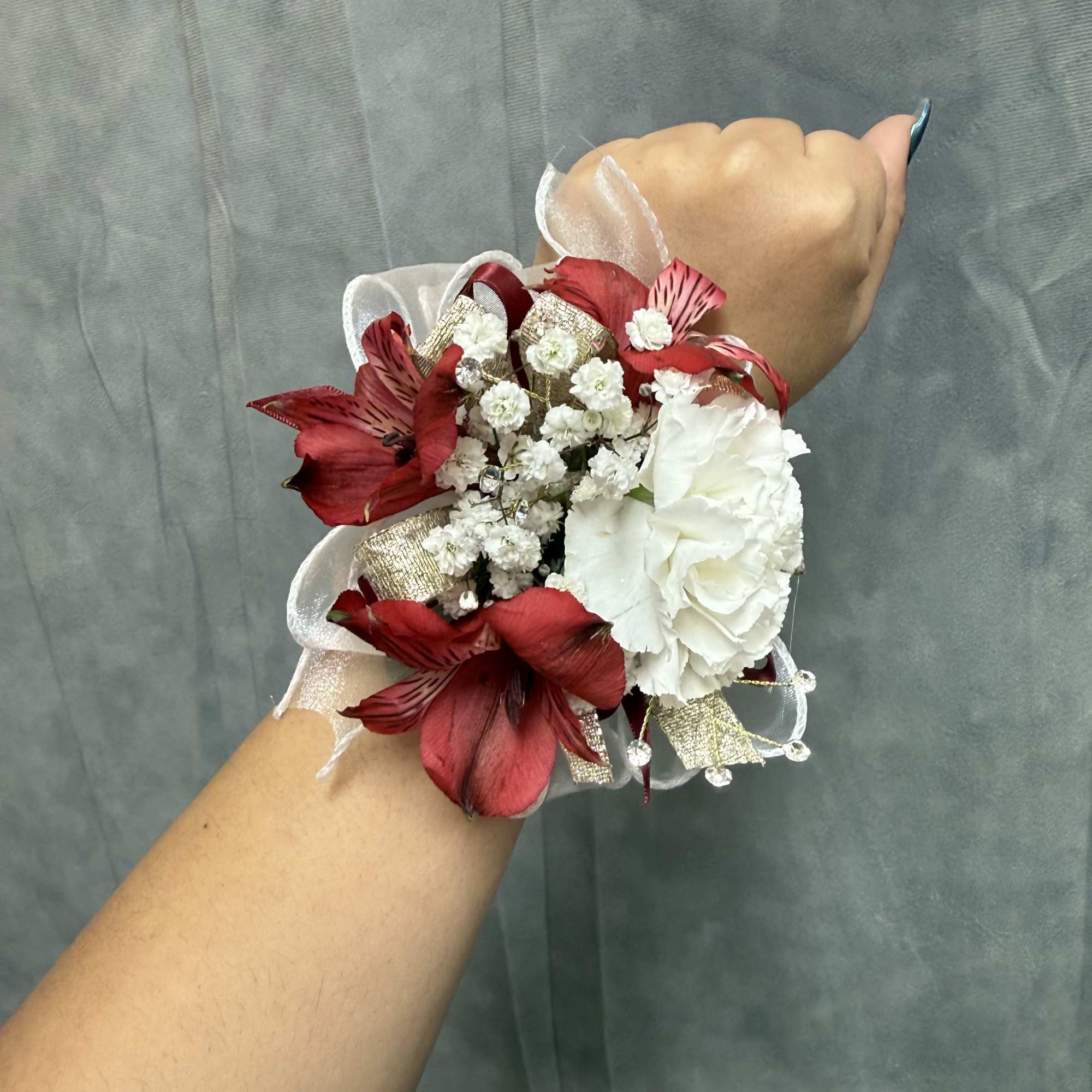 White carnation wrist corsage with red alstroemeria accents, gold accents , rhinestones, photo 2 of 2