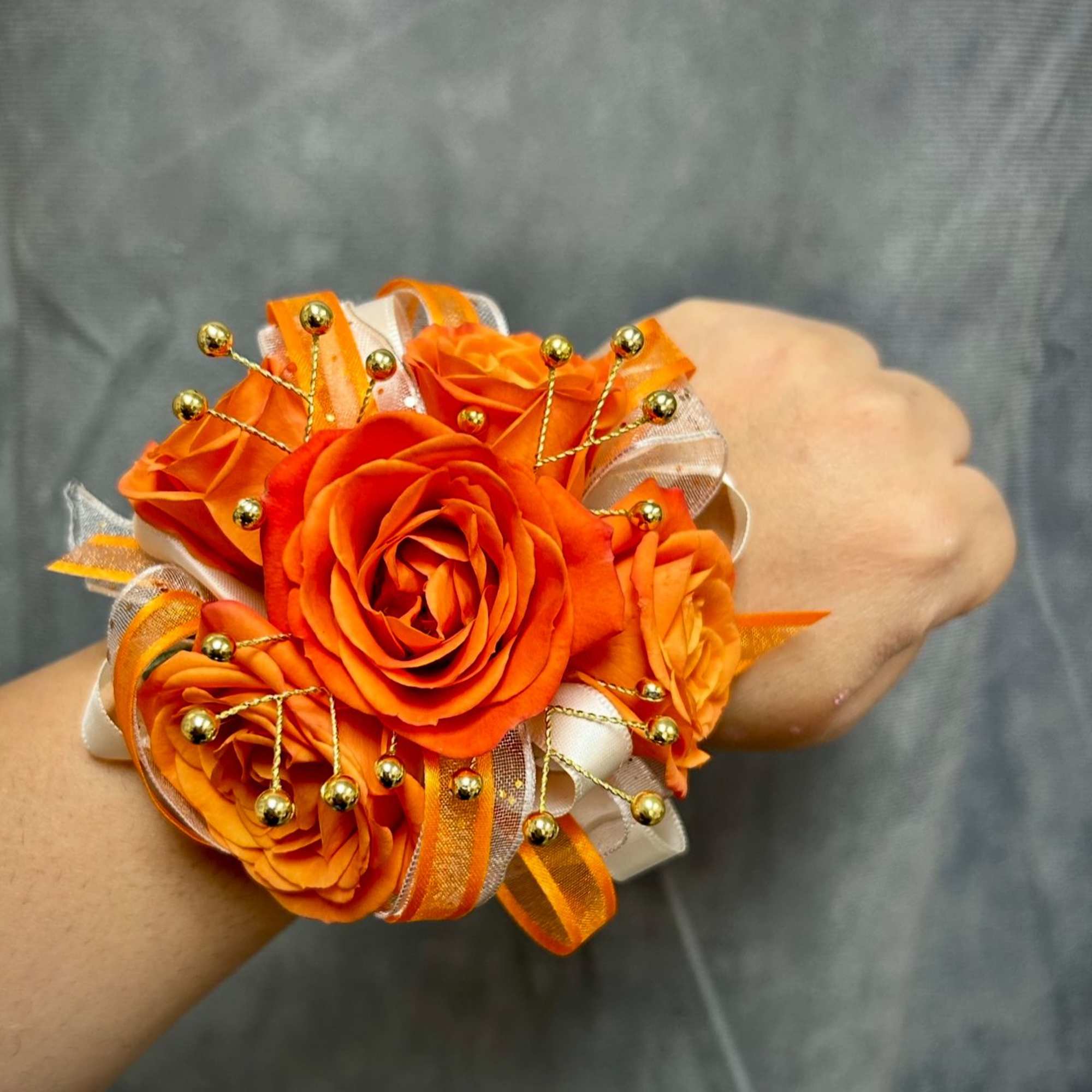Orange rose wrist corsage with ribbon and gold bead accents