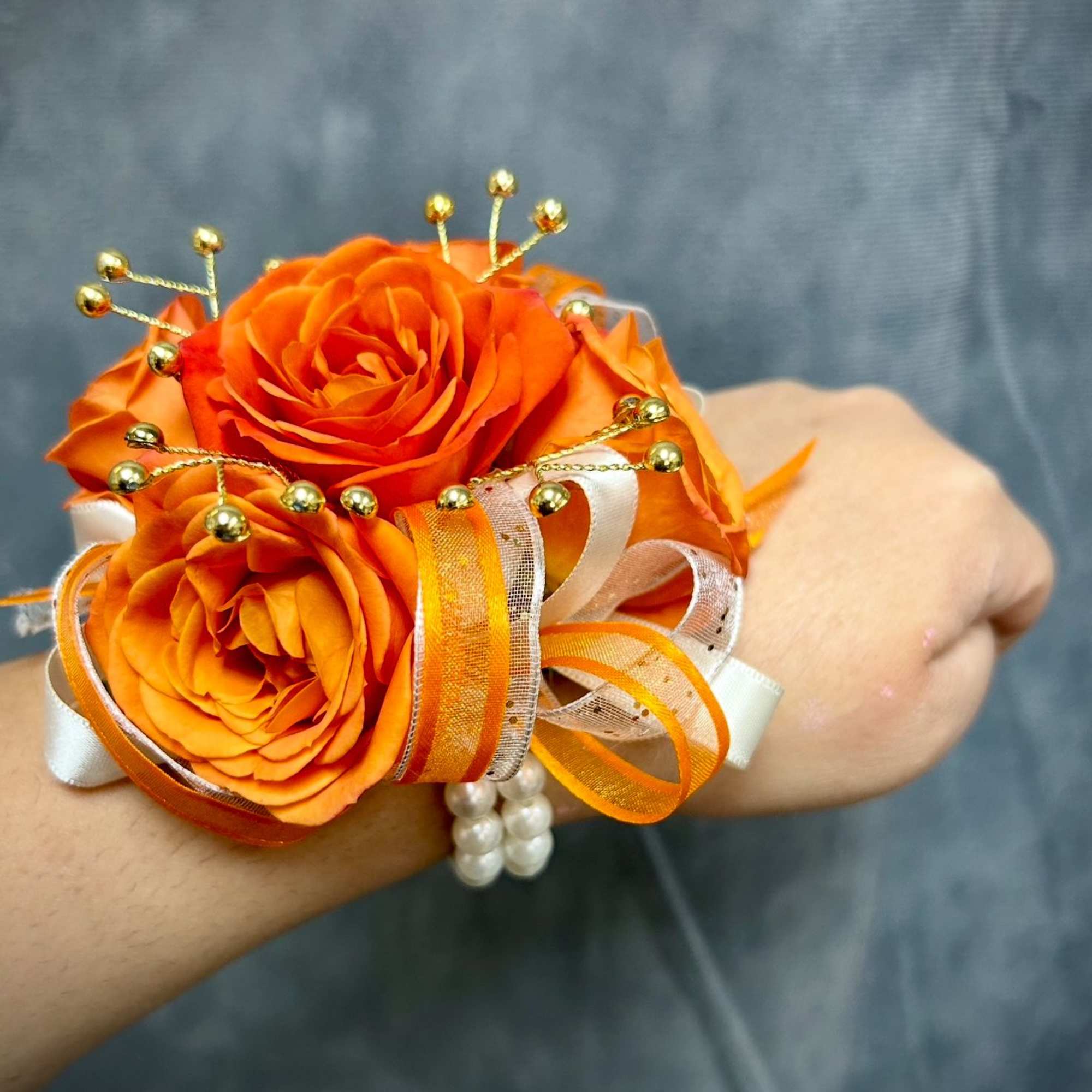 Orange rose wrist corsage with ribbon and pearl accents