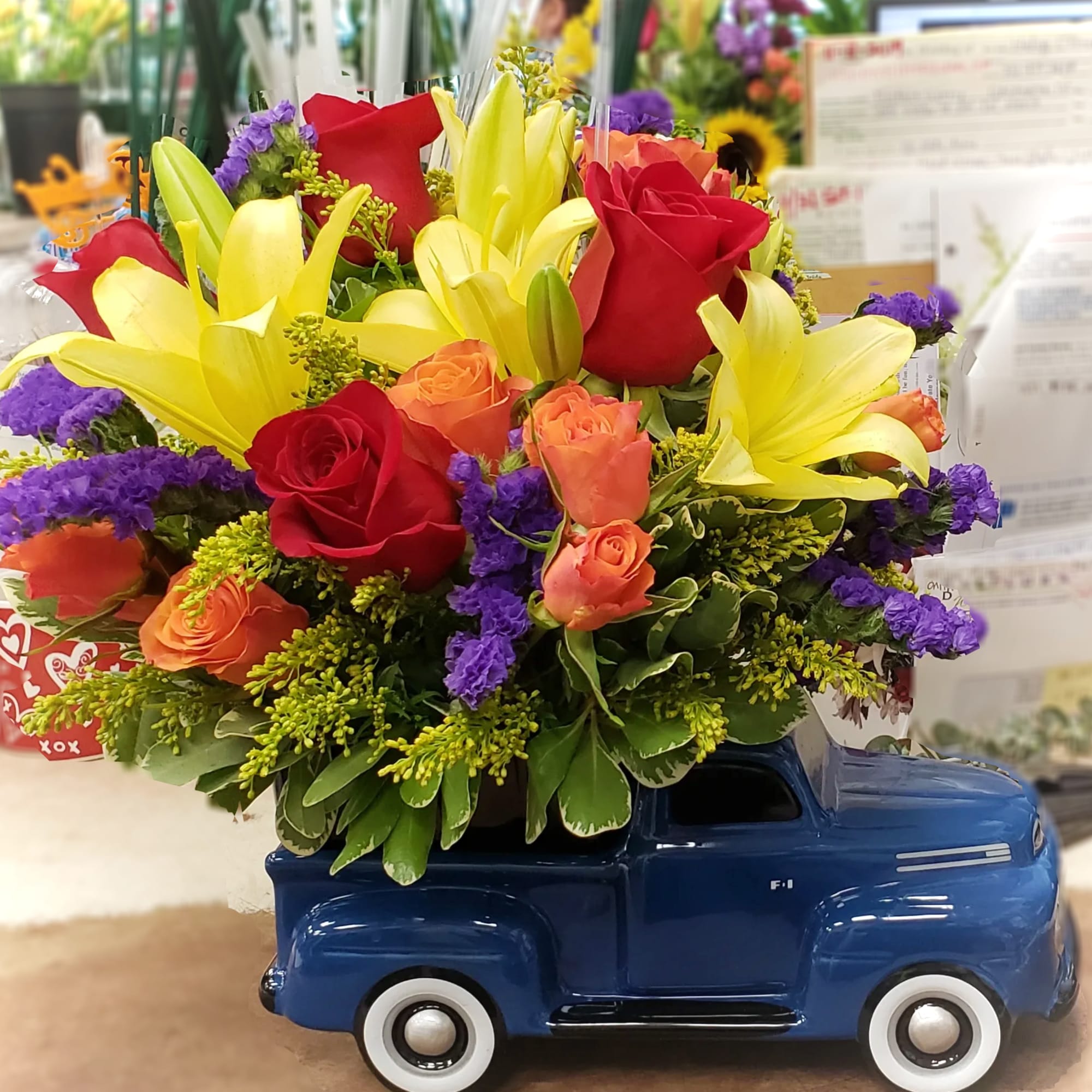 Bouquet of yellow lilies and red roses in a blue truck vase