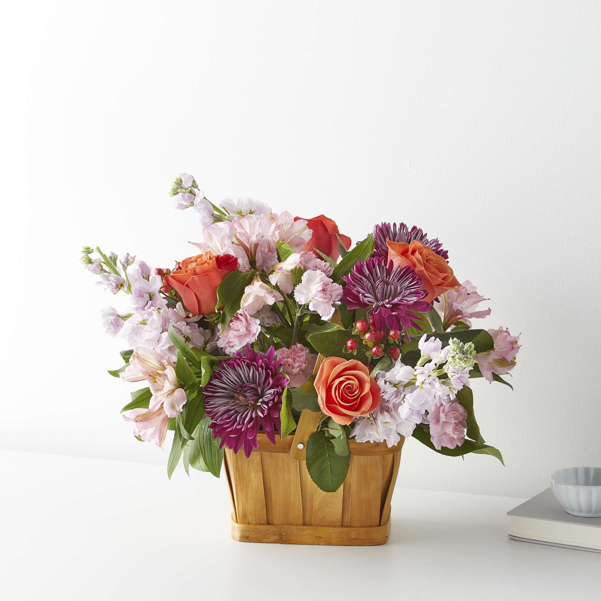 Mixed bouquet in a wooden basket with pink, orange, and purple flowers