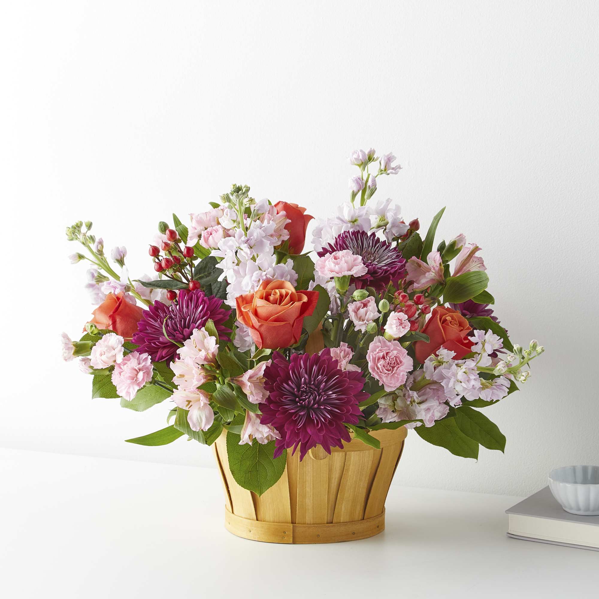 Mixed pink and orange flowers arranged in a wooden basket