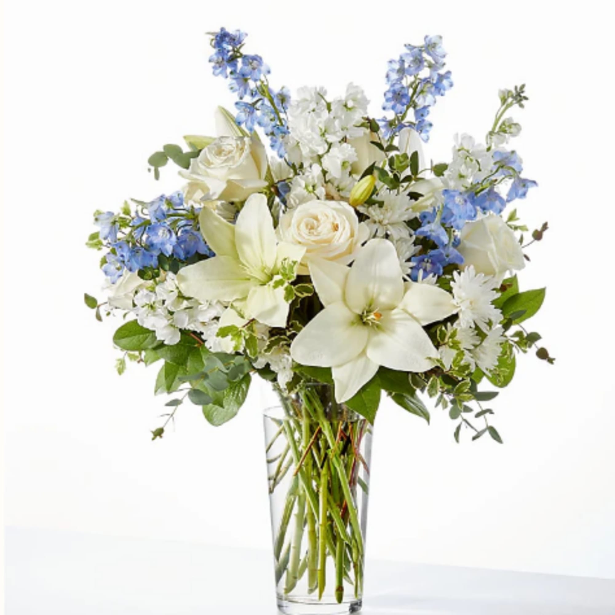 White and blue floral bouquet in a clear glass vase