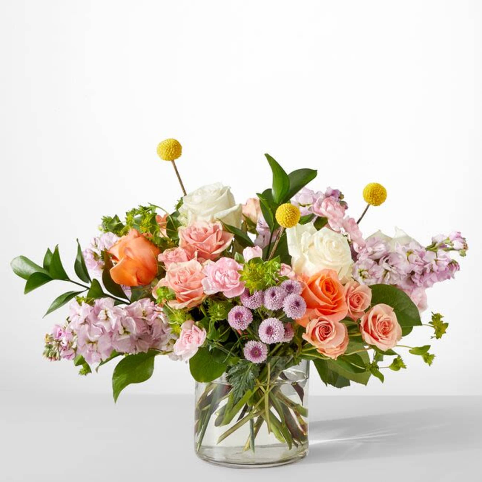 Mixed bouquet of roses and lavender flowers in a clear glass vase