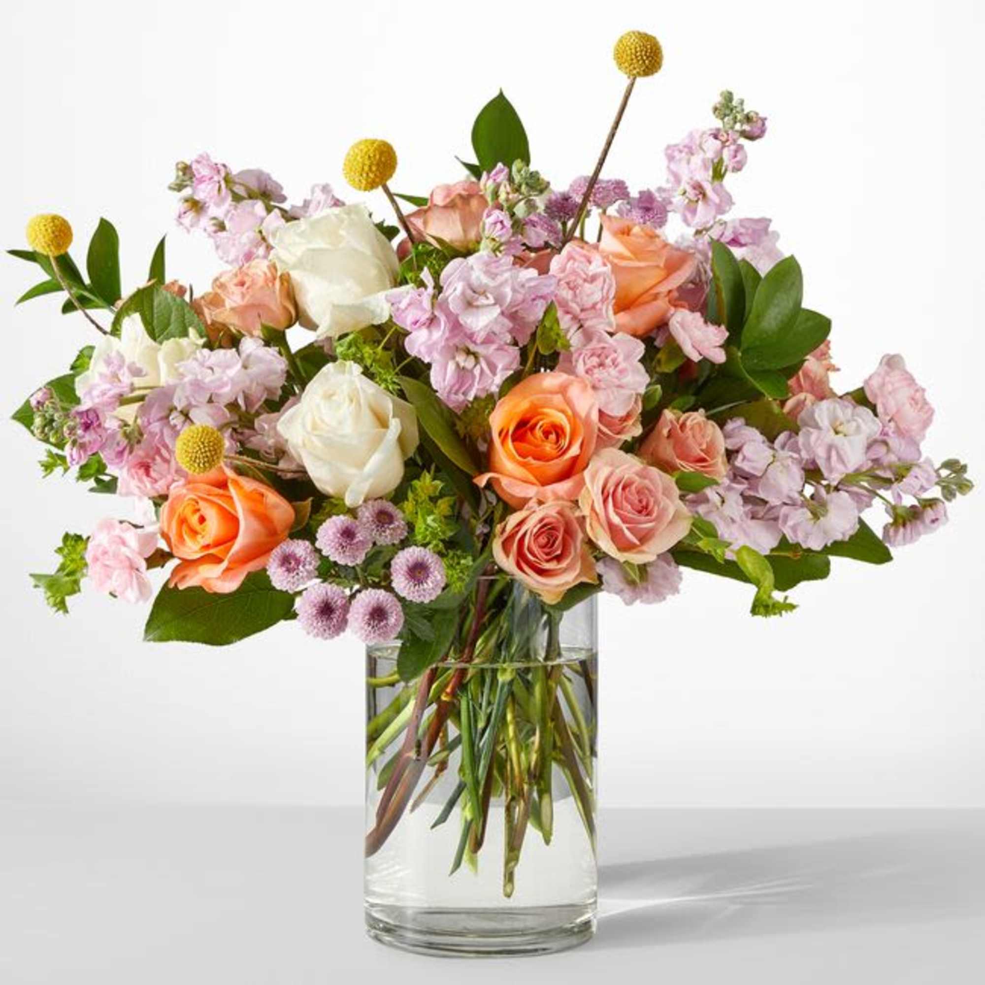 Mixed bouquet of roses and pink blooms in a clear glass vase