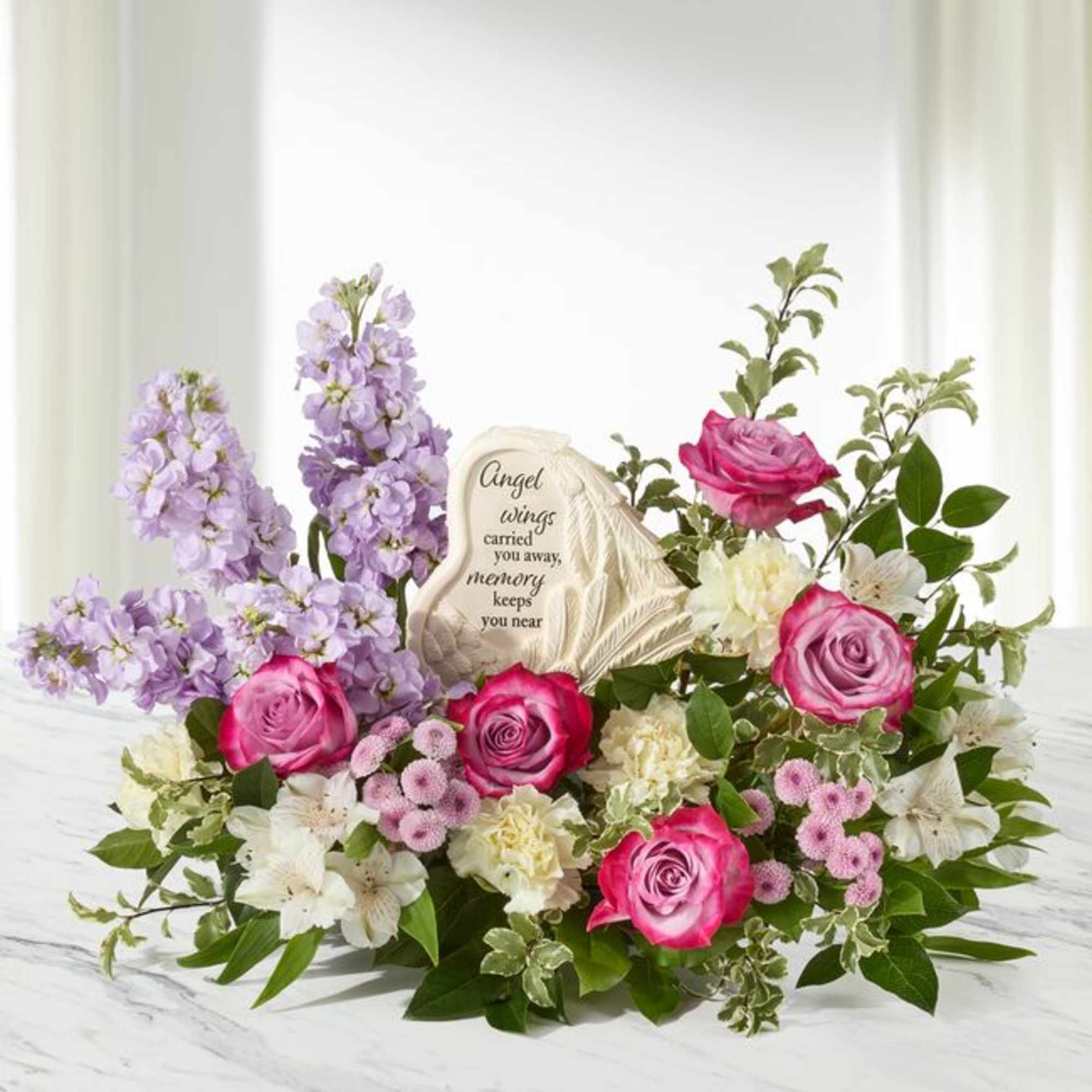 Pink roses and lavender flowers arranged around a memorial stone