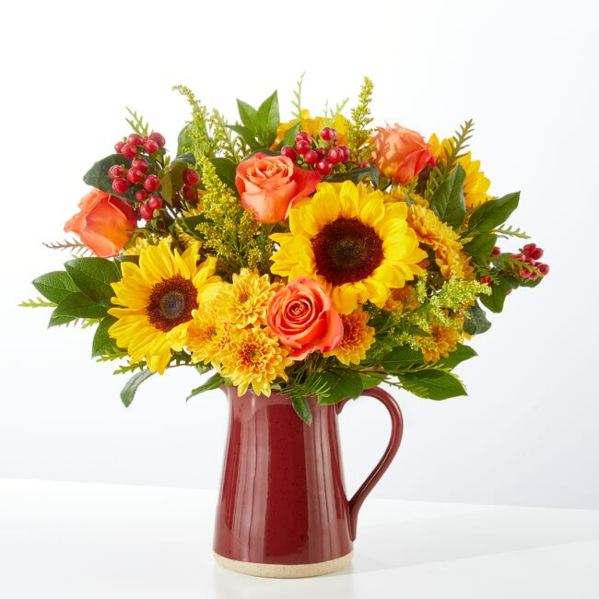 Sunflower and rose bouquet in a red ceramic pitcher