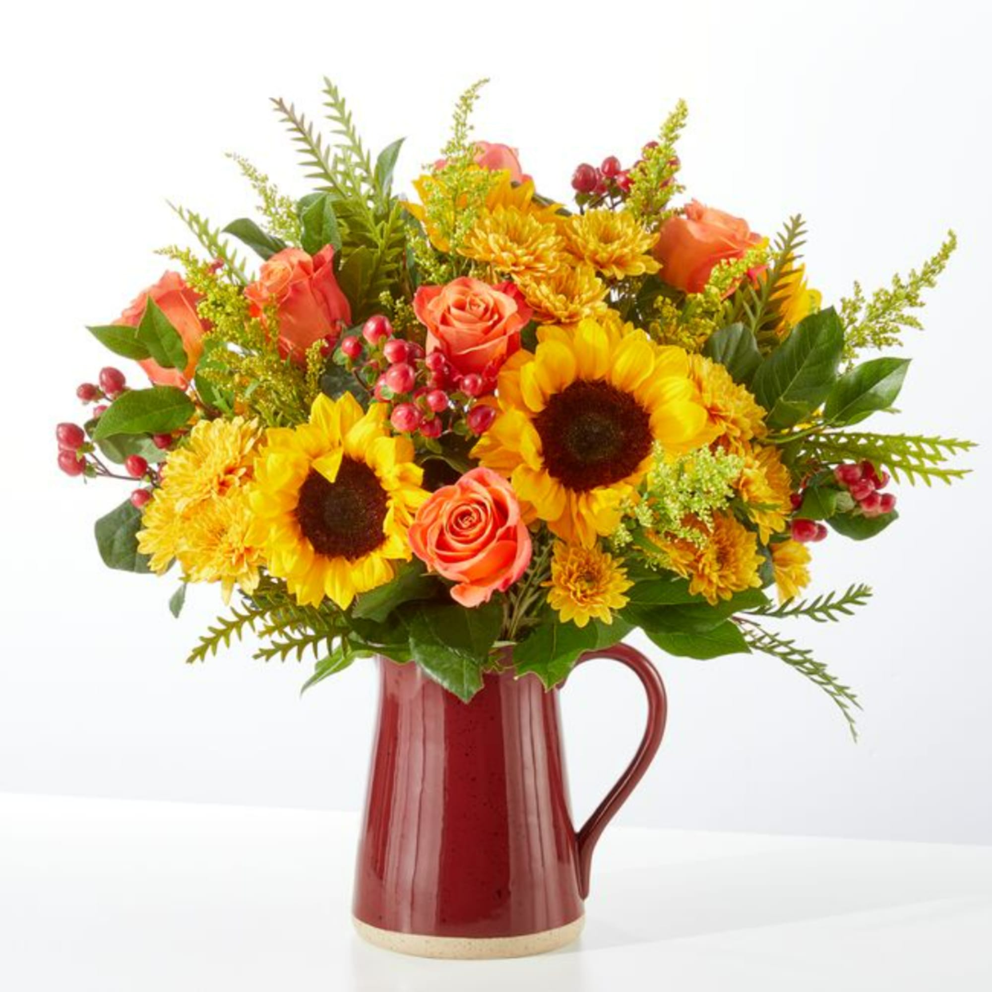 Sunflower and orange rose bouquet in a red ceramic pitcher