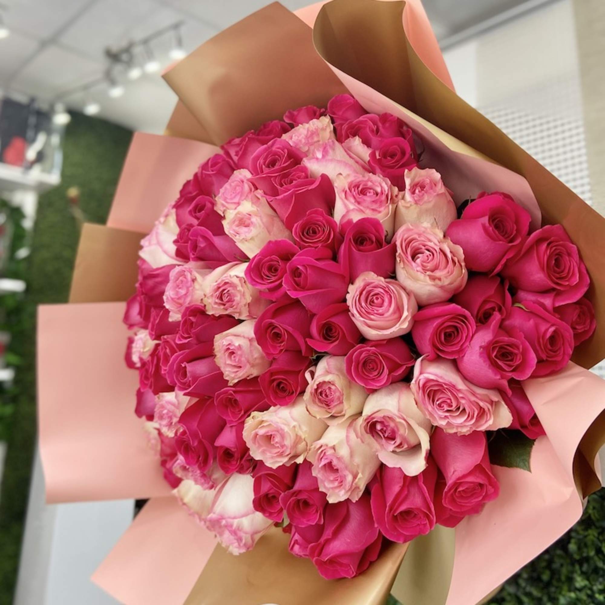 Large hand-tied bouquet of hot pink and light pink roses wrapped in blush and gold paper