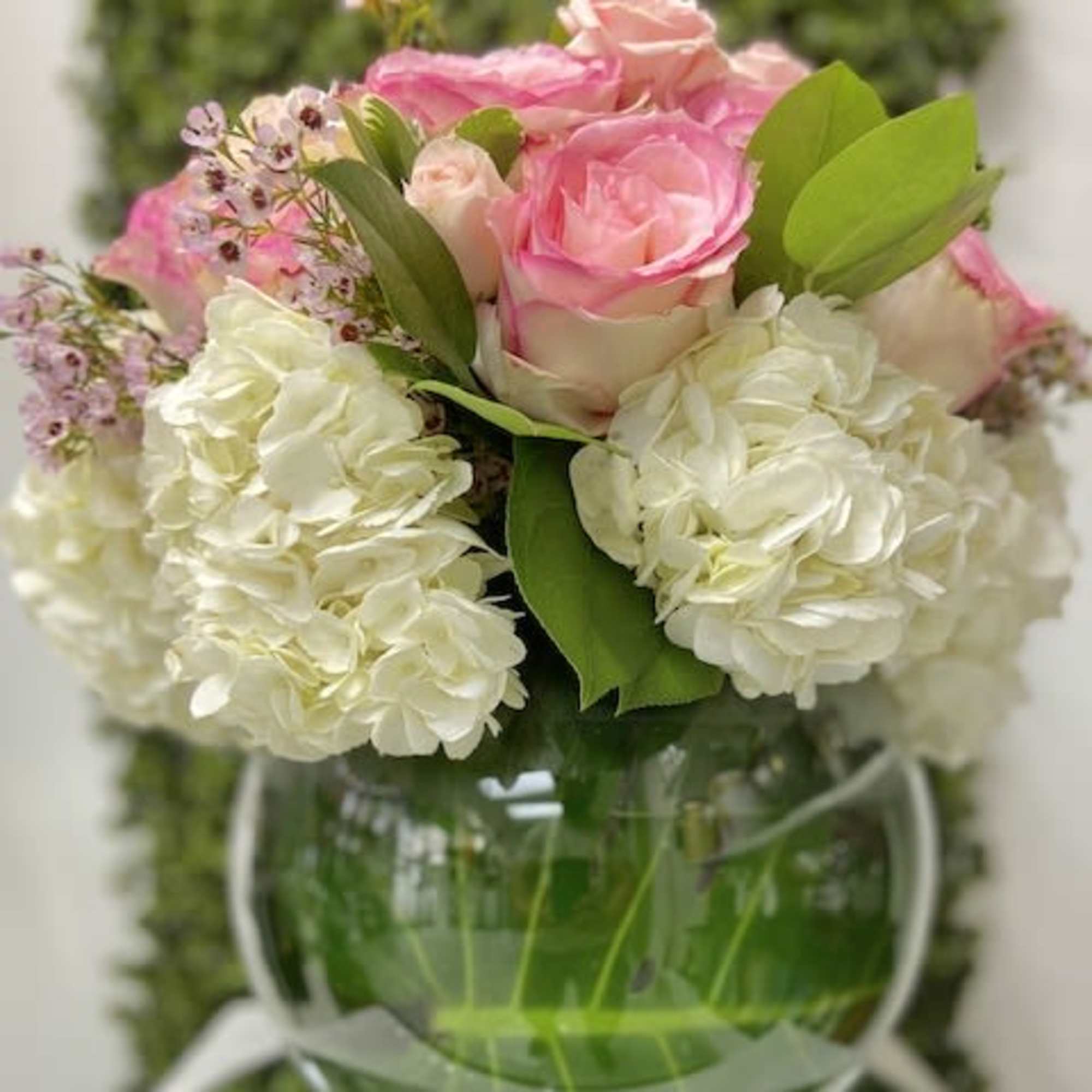 Round bowl vase with pink roses and white hydrangeas arranged in a low, full dome