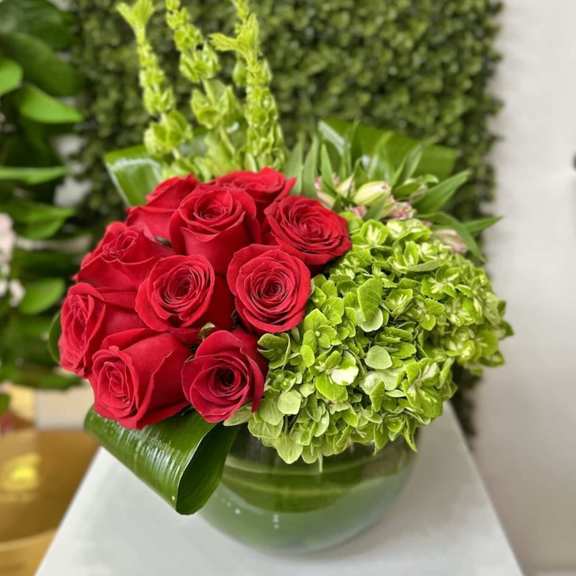Low arrangement of red roses and green hydrangeas in a round glass vase, photo 2 of 3