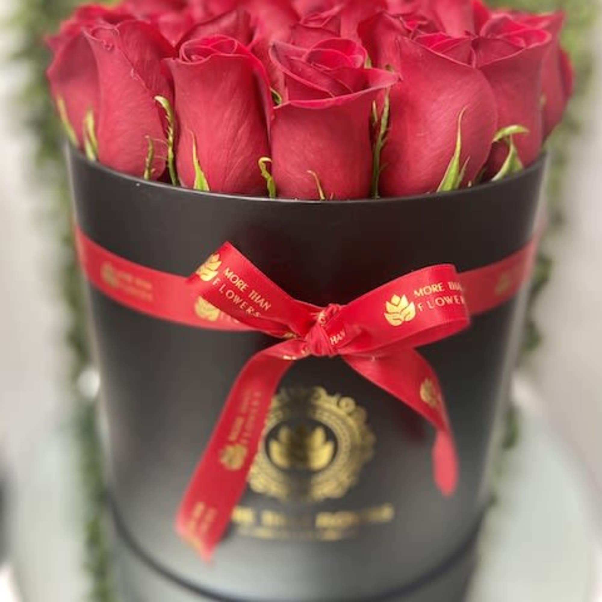 Round black box filled with upright red roses and tied with a red ribbon