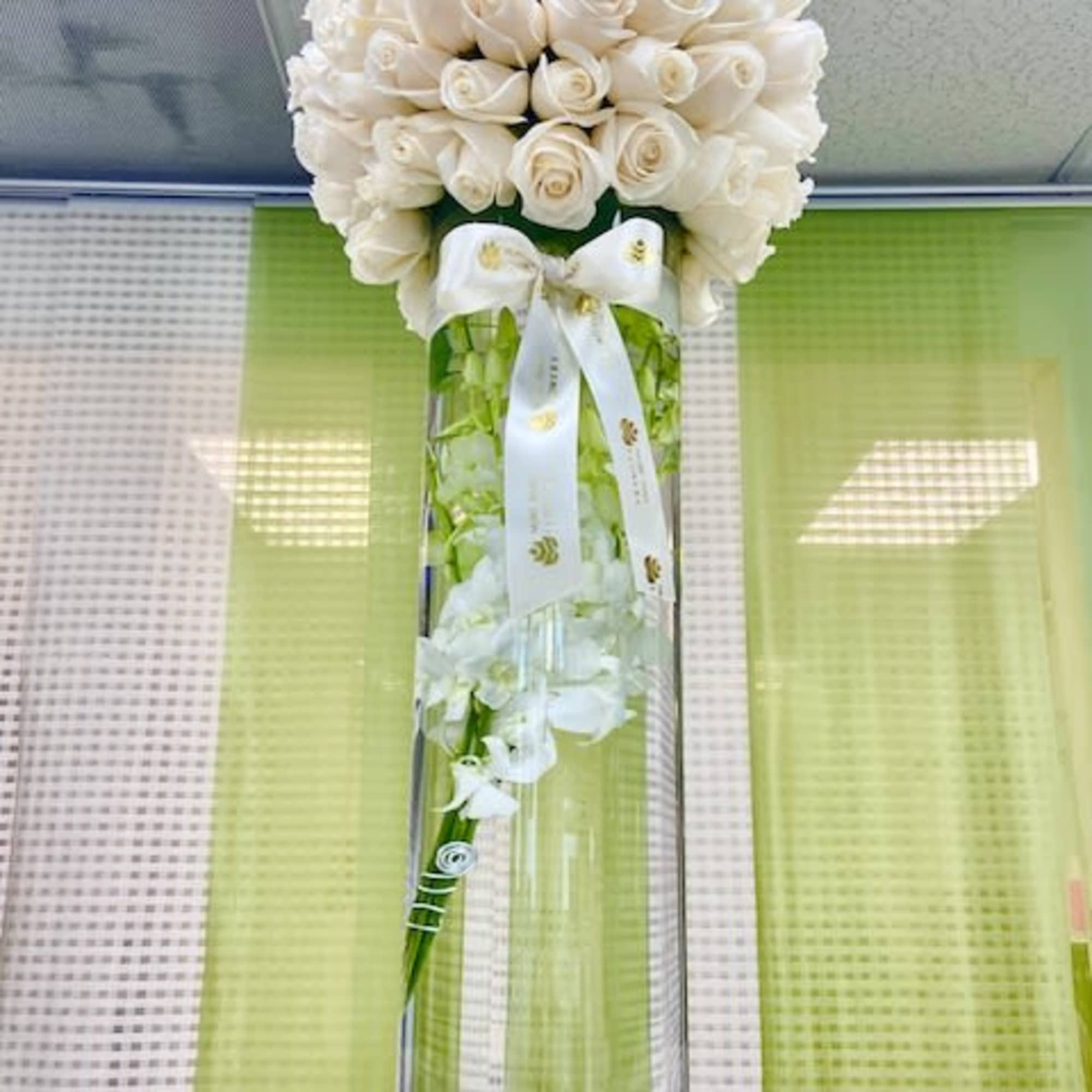 Tall glass vase with a dome of white roses and submerged white orchids.