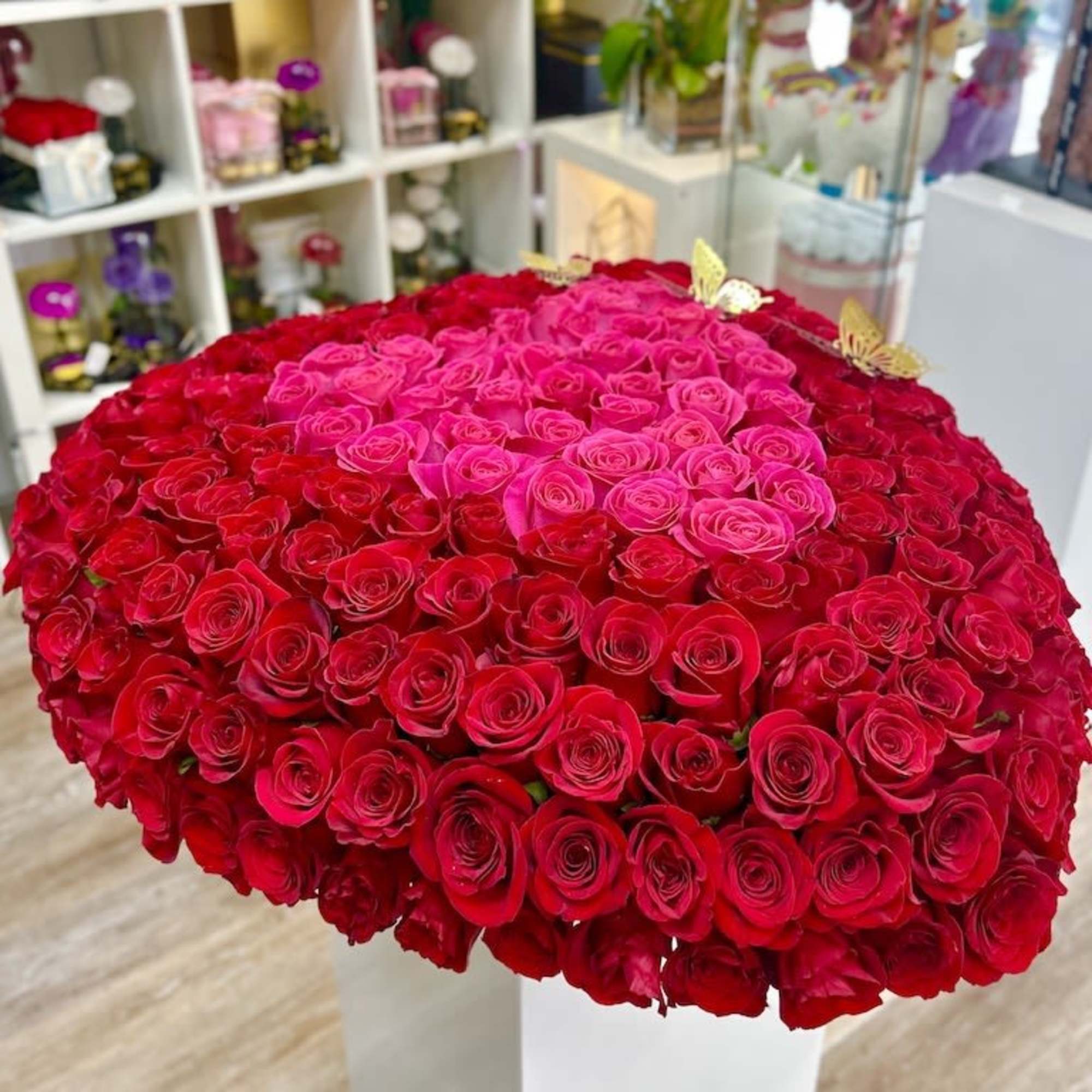 Large heart-shaped arrangement of red and hot pink roses on a white pedestal.