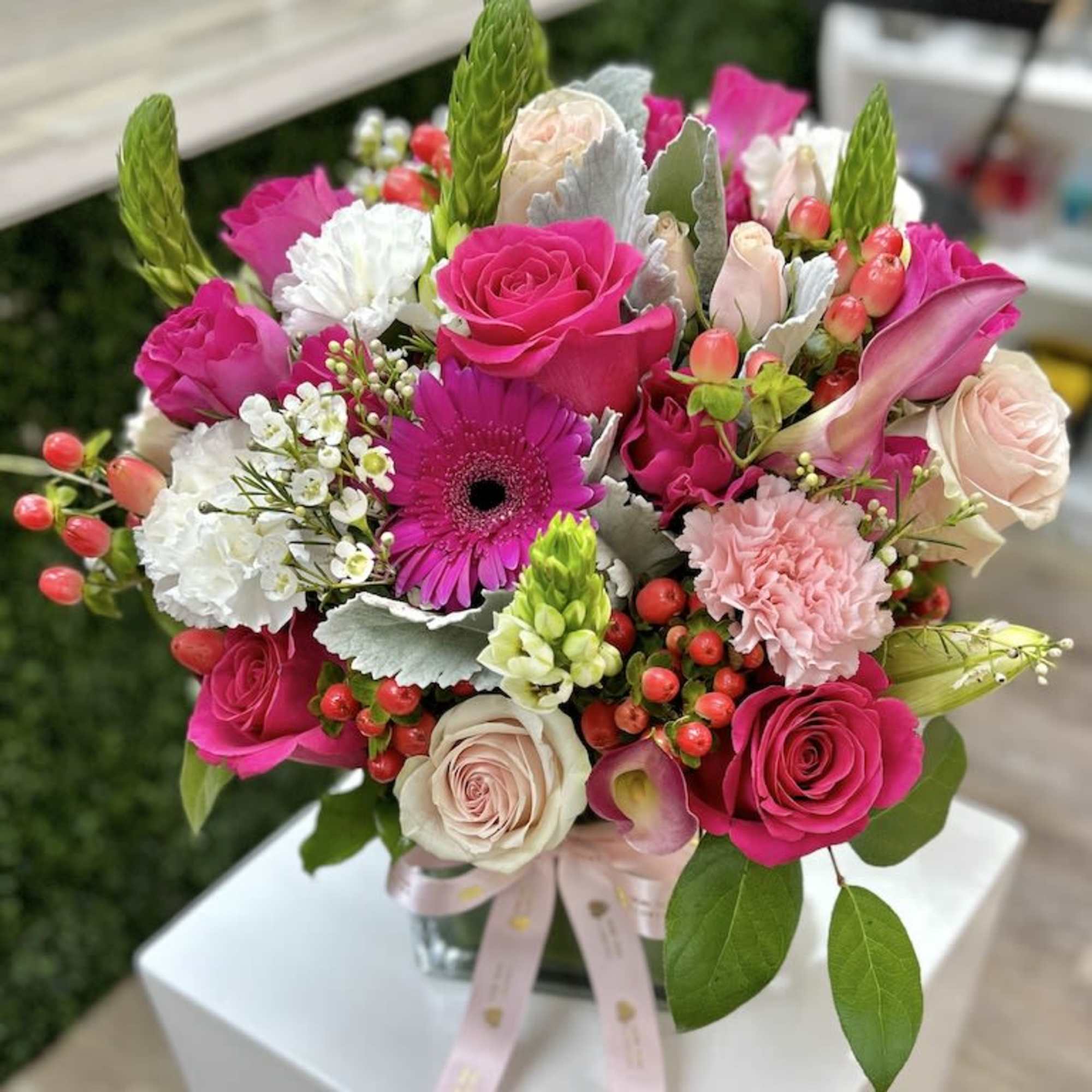 Bright pink and white mixed flower arrangement with roses and gerbera daisy in a glass vase with pink ribbon