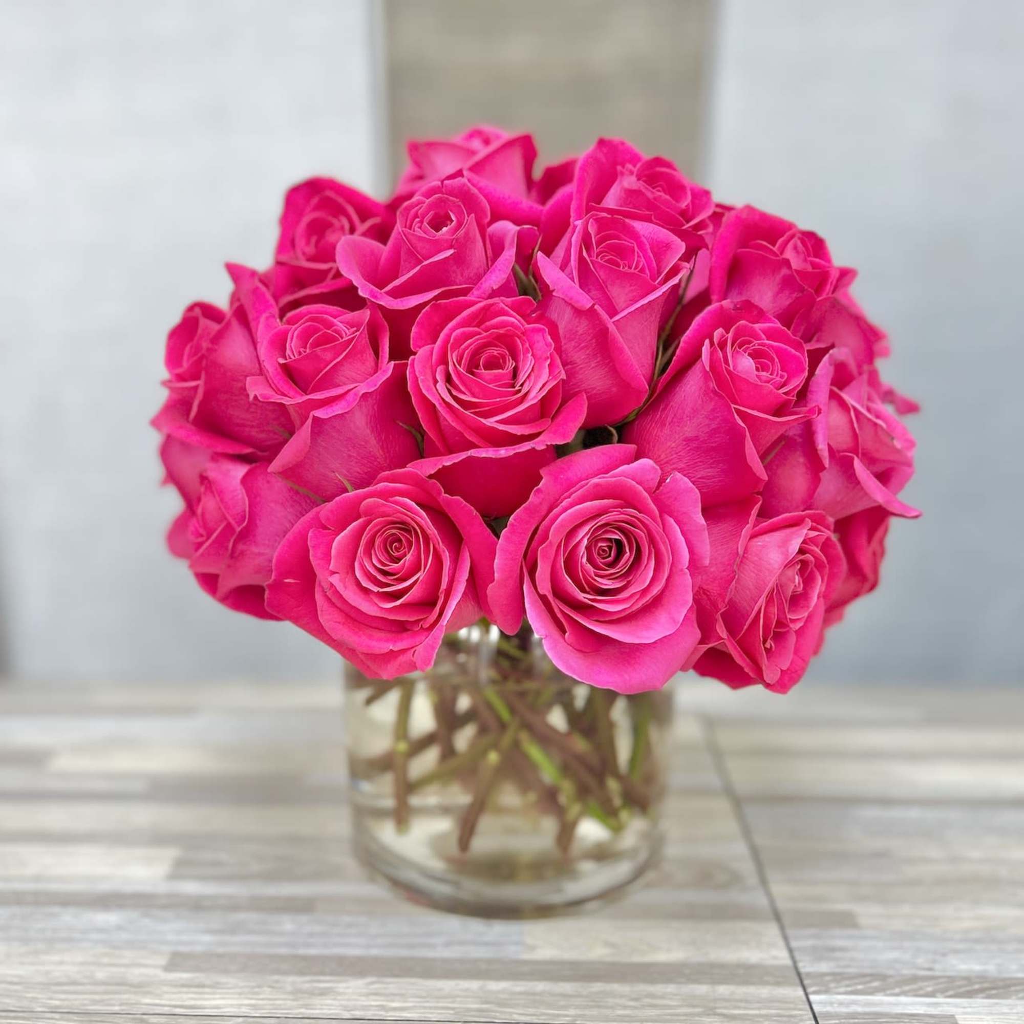 Compact bouquet of bright pink roses arranged in a clear glass vase