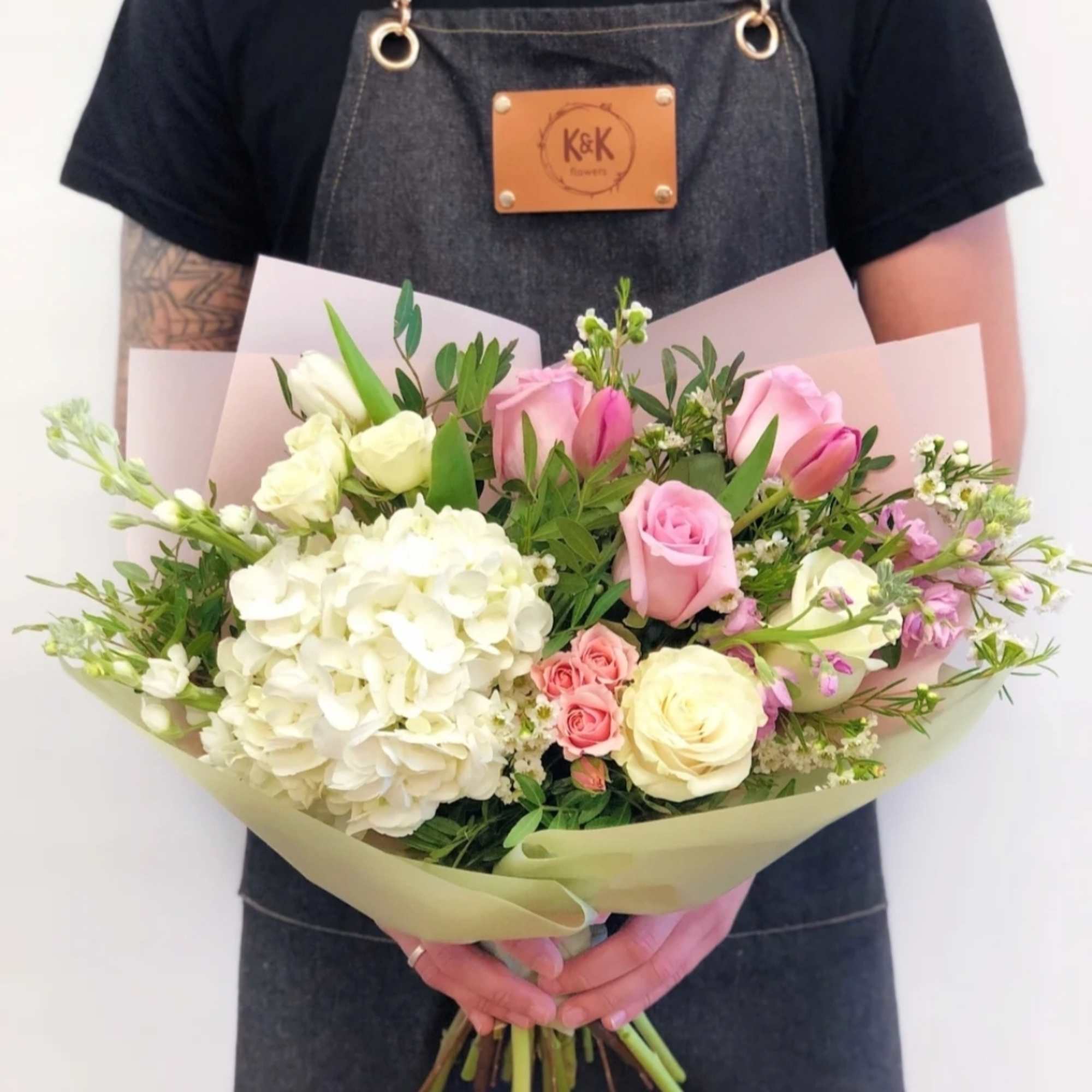 Handheld bouquet of pink and white roses with white hydrangea