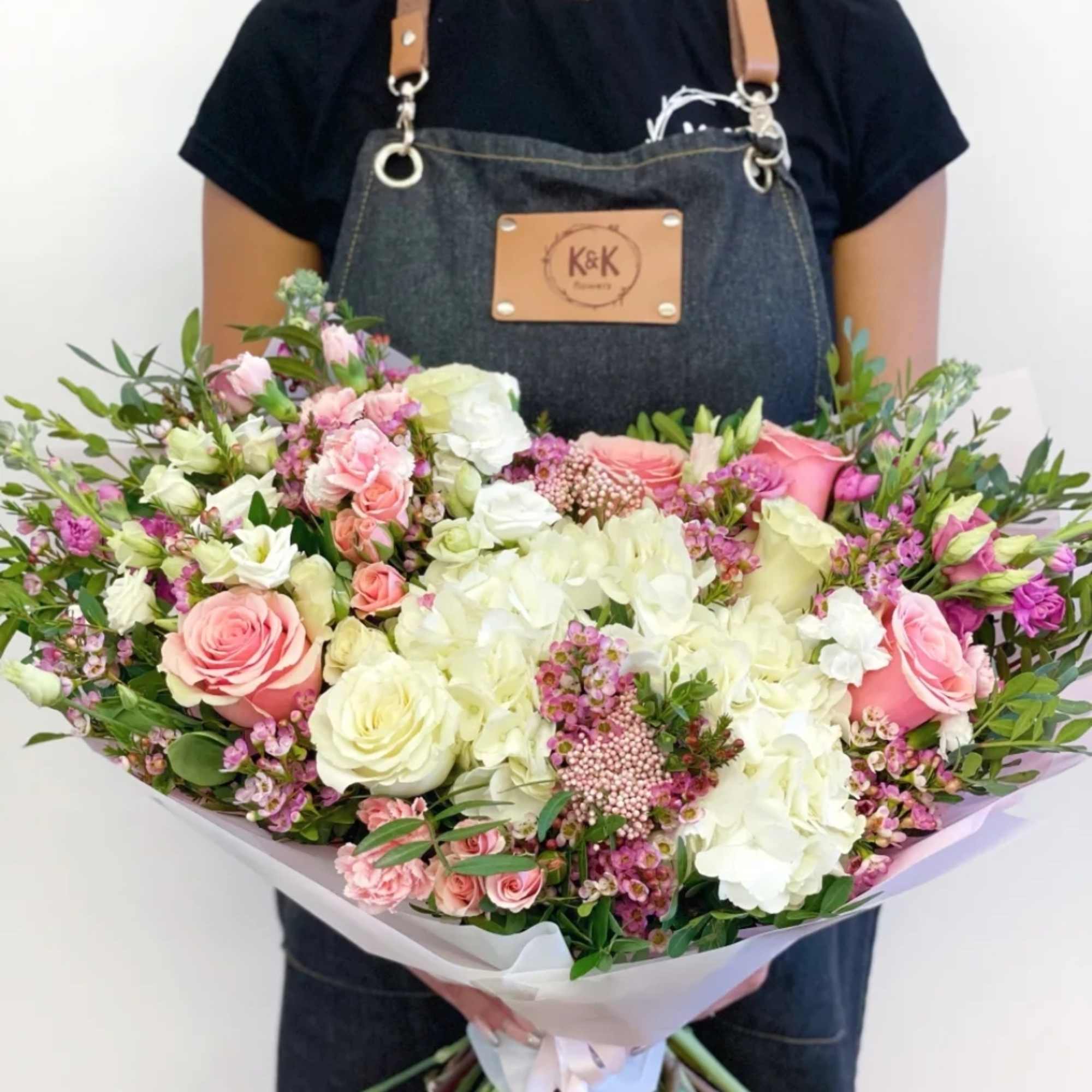 Large bouquet of pink and white roses with mixed blooms wrapped in paper
