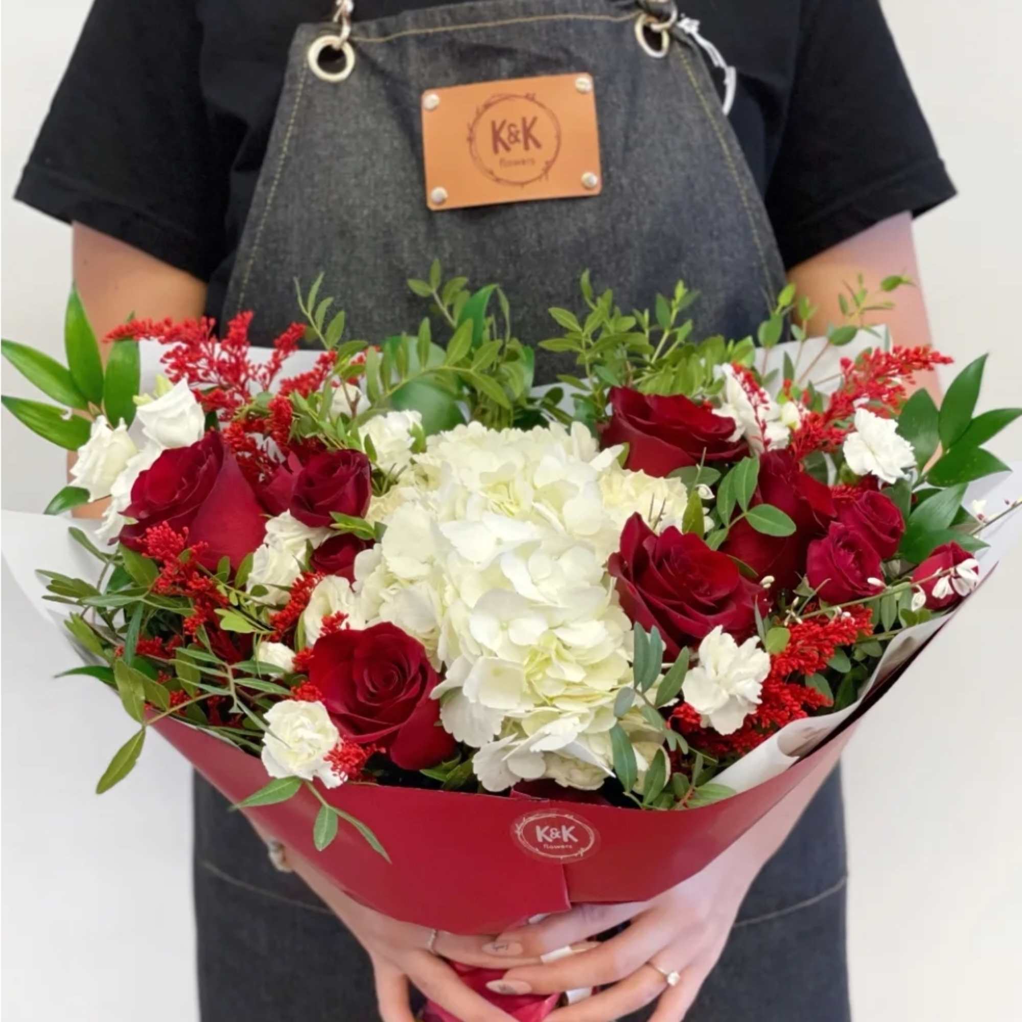 Bouquet of red roses and white hydrangeas wrapped in red paper