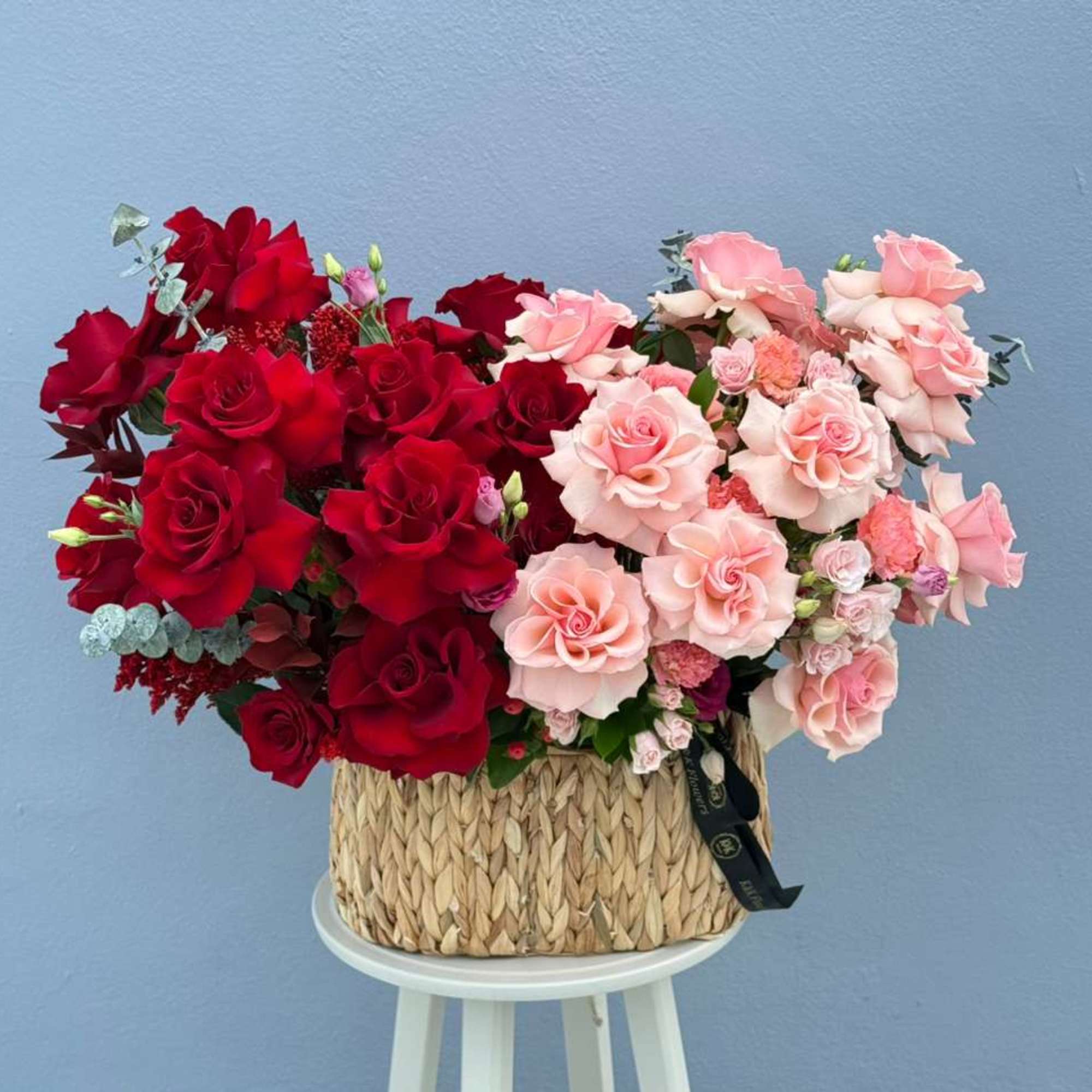 A modern bi-color basket arrangement featuring premium French roses in soft blush