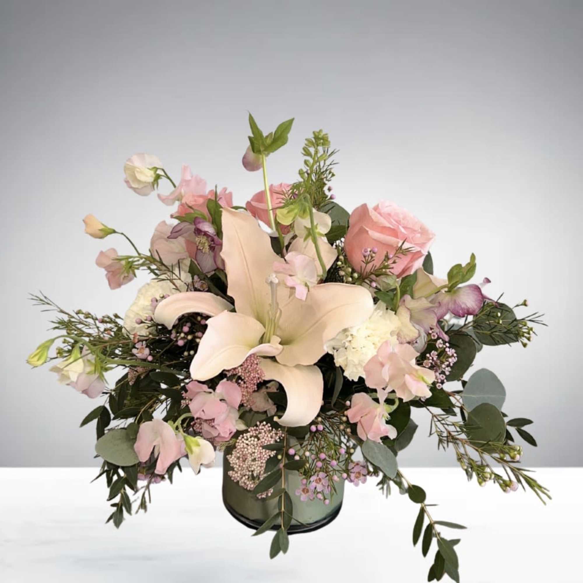 A romantic floral centerpiece featuring blush roses, lilies, tulips, and fresh greenery, photo 2 of 2