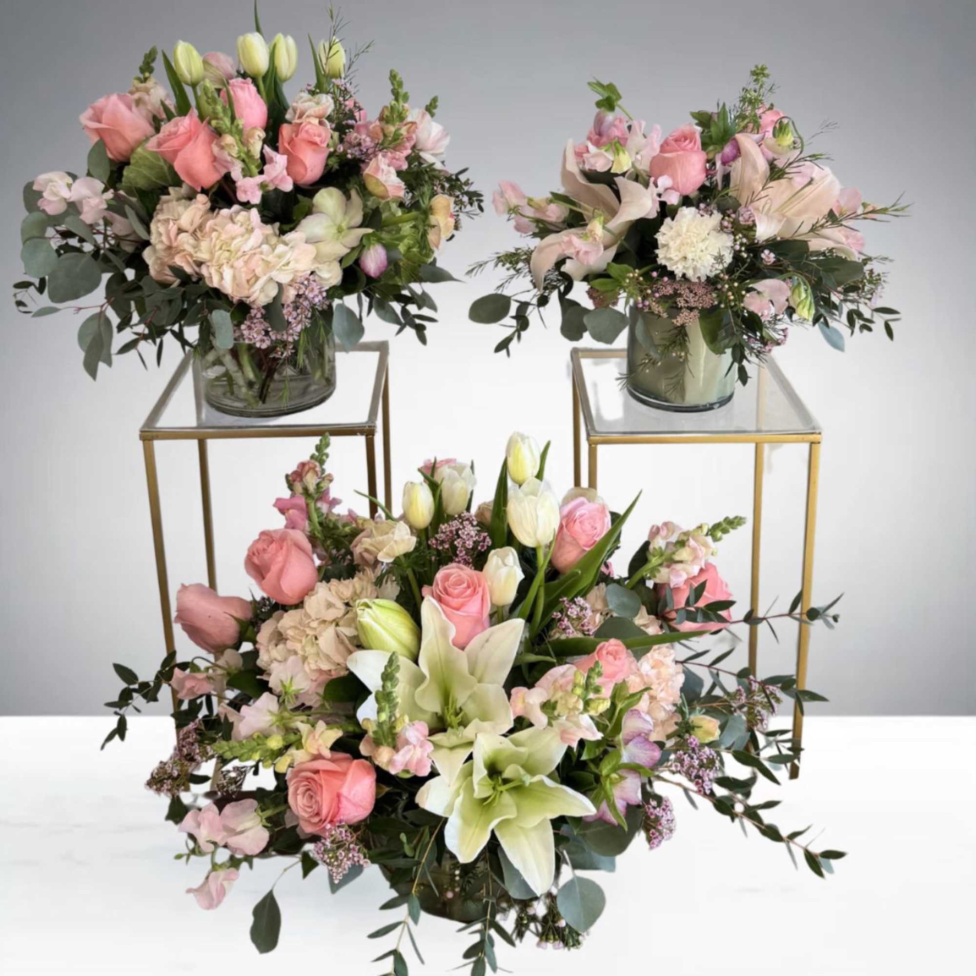 A romantic floral centerpiece featuring blush roses, lilies, tulips, and fresh greenery