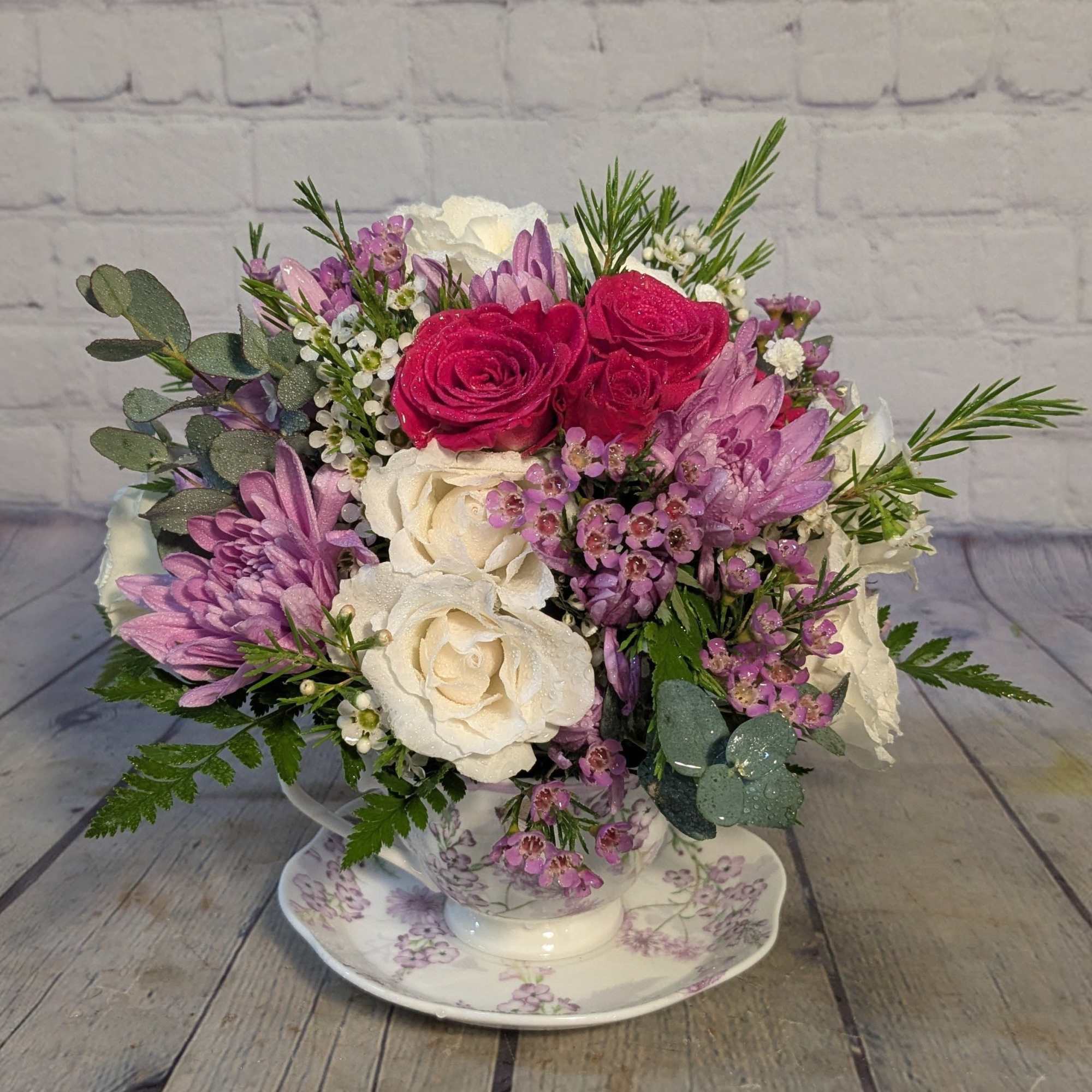 Bouquet of pink, white, and purple flowers in a teacup on a saucer