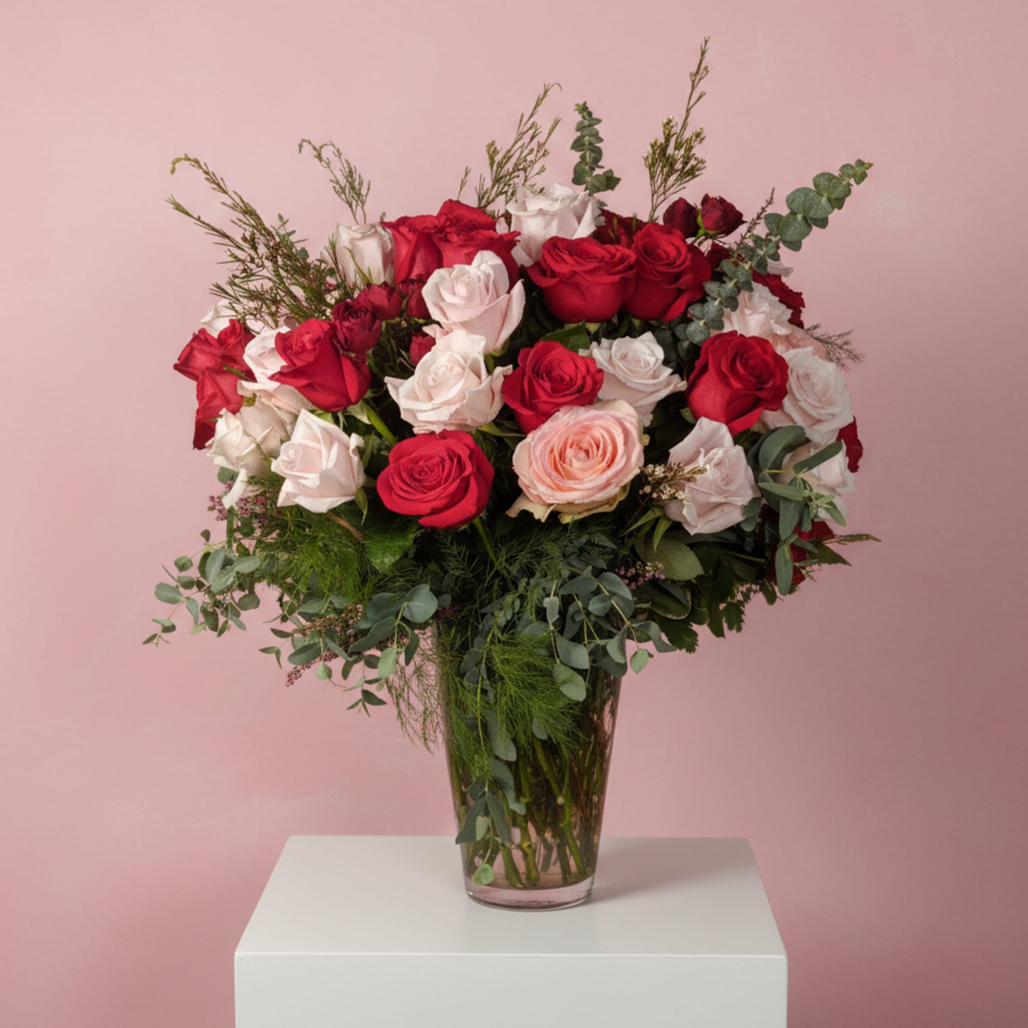 Bouquet of red and blush roses in a clear glass vase