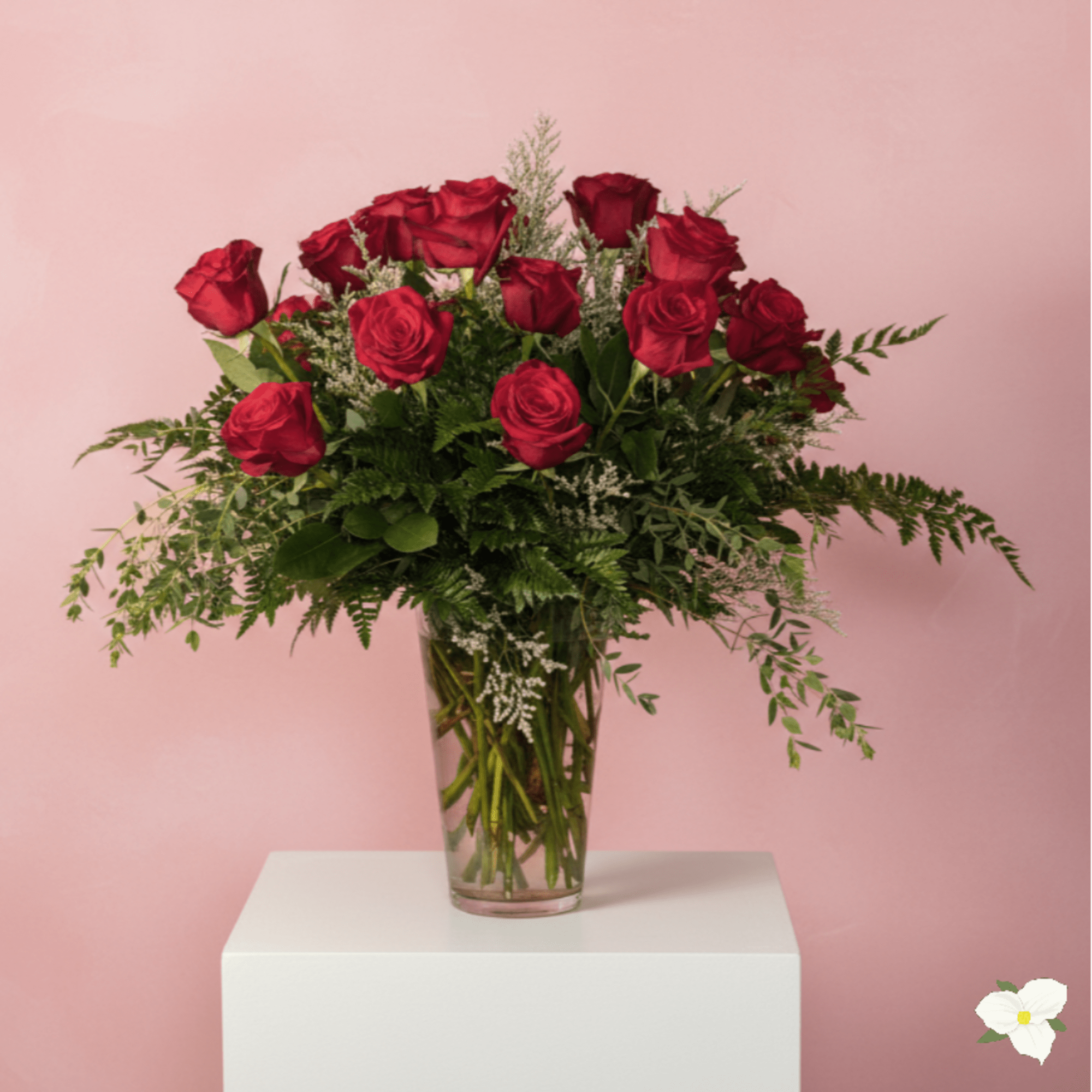Red roses arranged in a clear glass vase with greenery