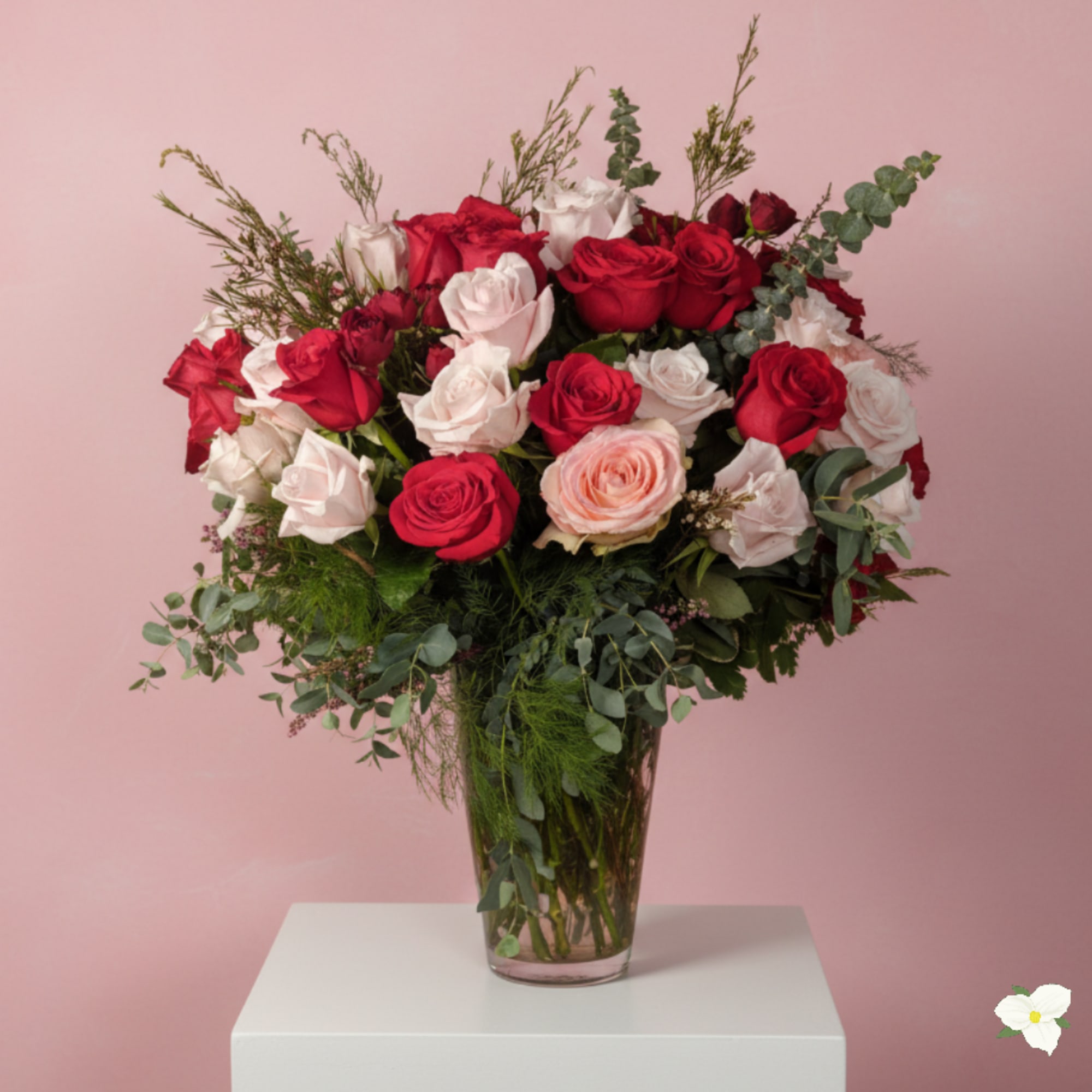Bouquet of red, white, and blush roses in a clear glass vase