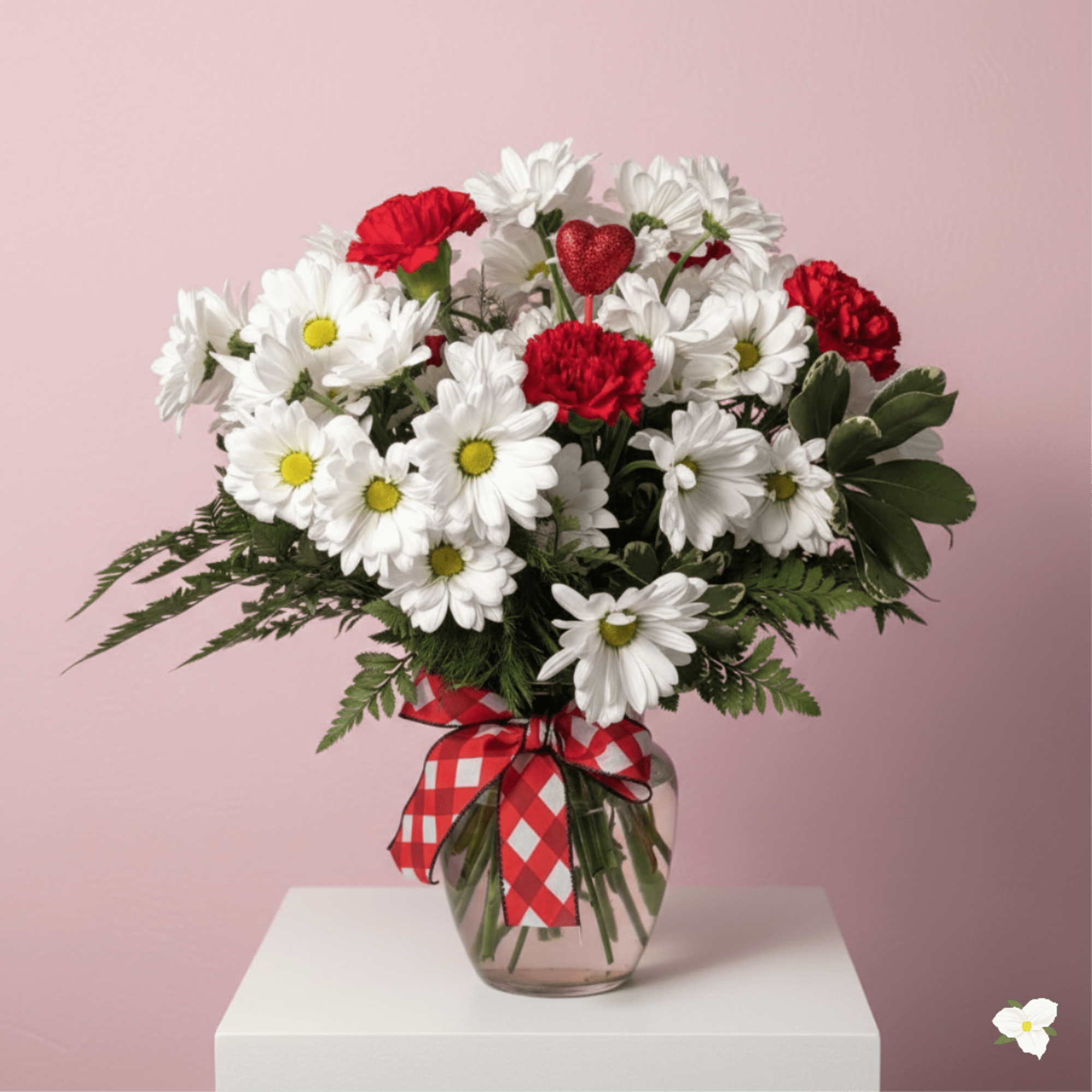 Bouquet of white daisies and red carnations in a glass vase with a red ribbon